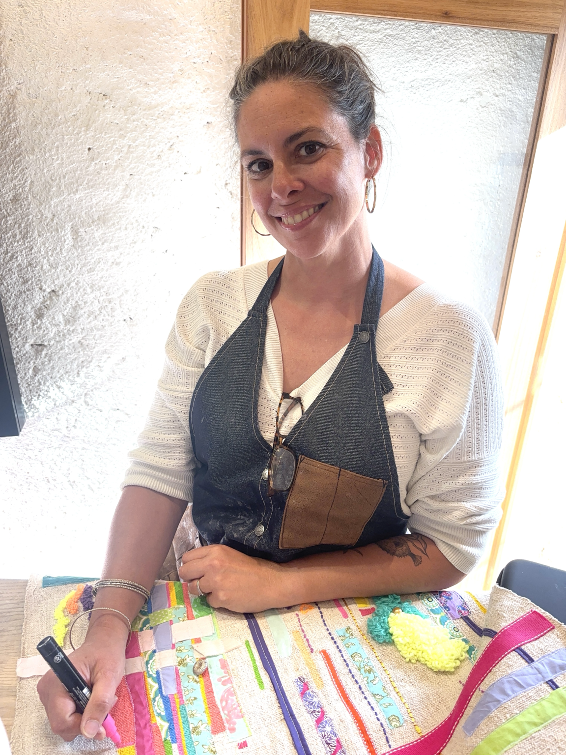 Mylièse Rolland, artiste textile, dans son atelier à Calvi en Corse, devant l’une de ses œuvres colorées.