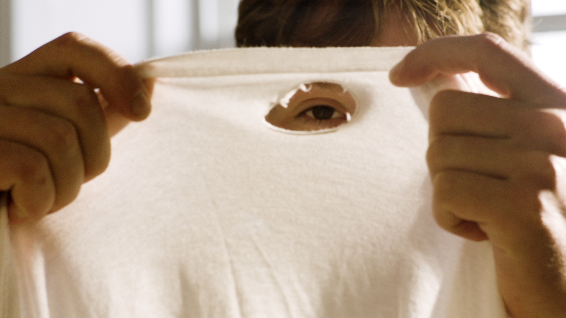 Person peeking through a hole in a paper mask.