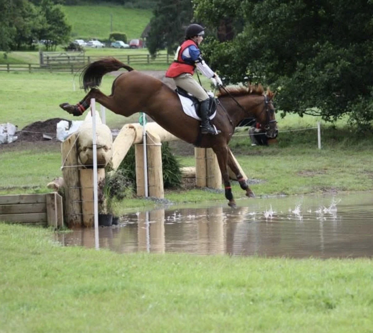 A rider and horse jumping into water during an equestrian event.