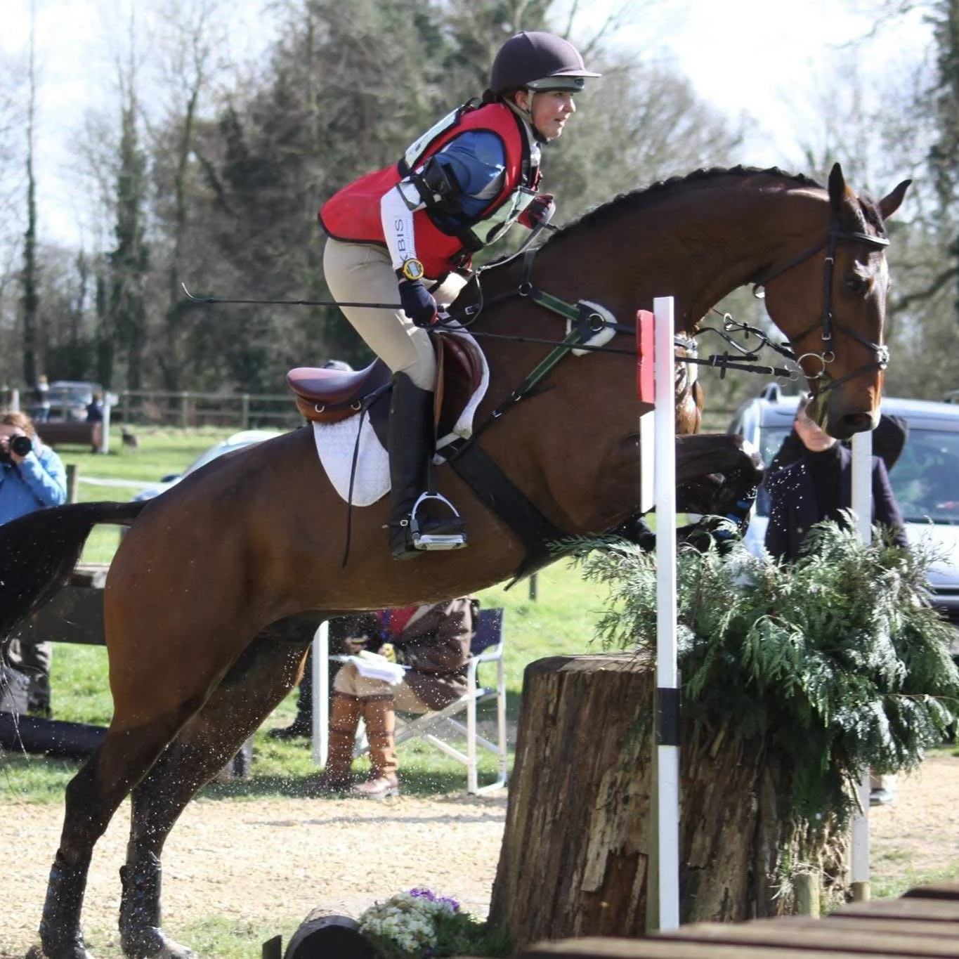 A person riding a horse jumping over an obstacle in an outdoor equestrian event.