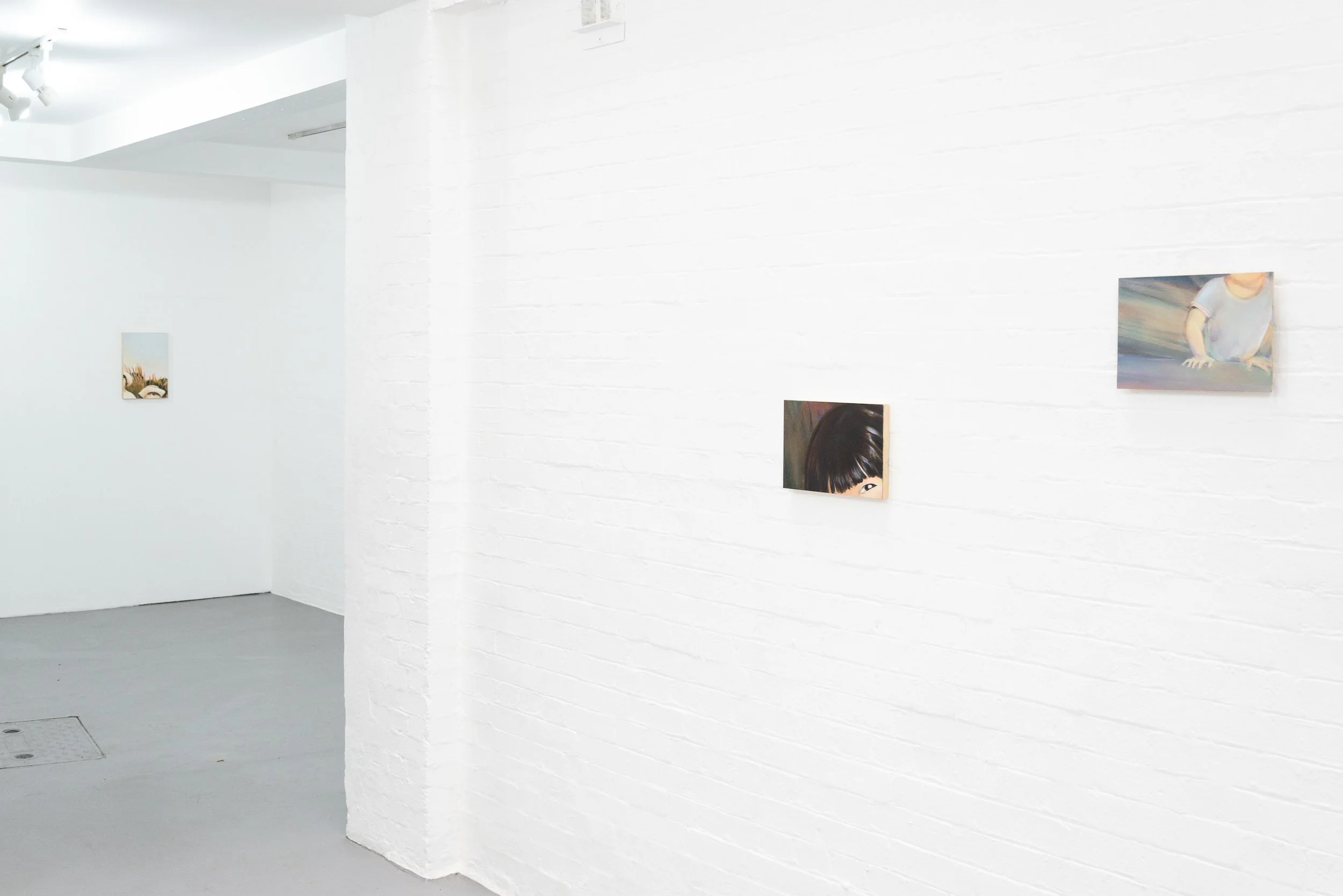 White gallery walls displaying portraits and artwork in an art exhibition space with minimalist decor.