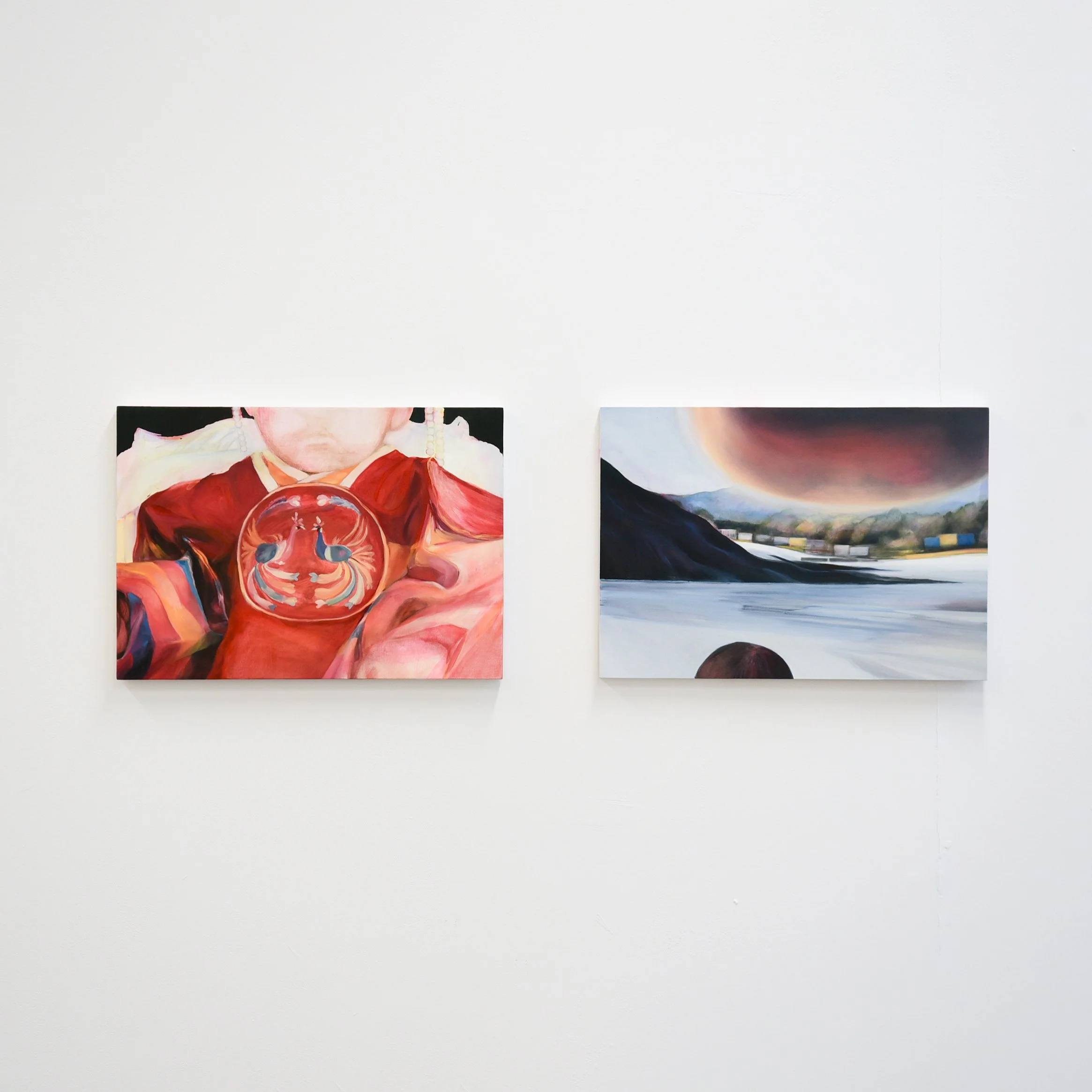 Two paintings hung on a plain white wall, one depicting a person with a pink face and red clothing and the other showing a colorful landscape with a swirling sky and water.