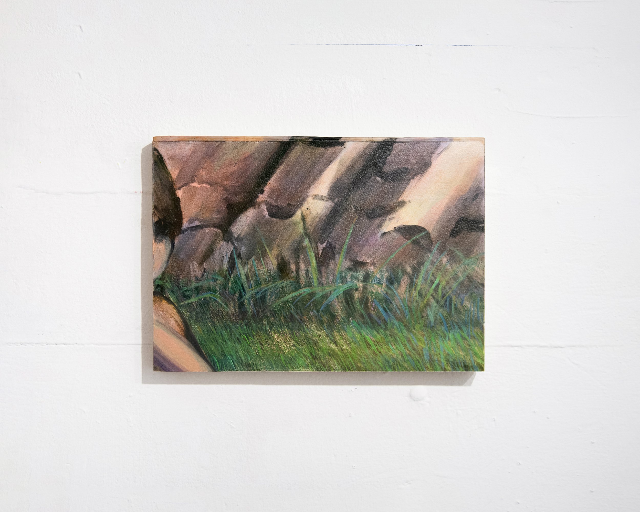 A small painting or print featuring abstract, earthy and green tones, hung on a white wall.