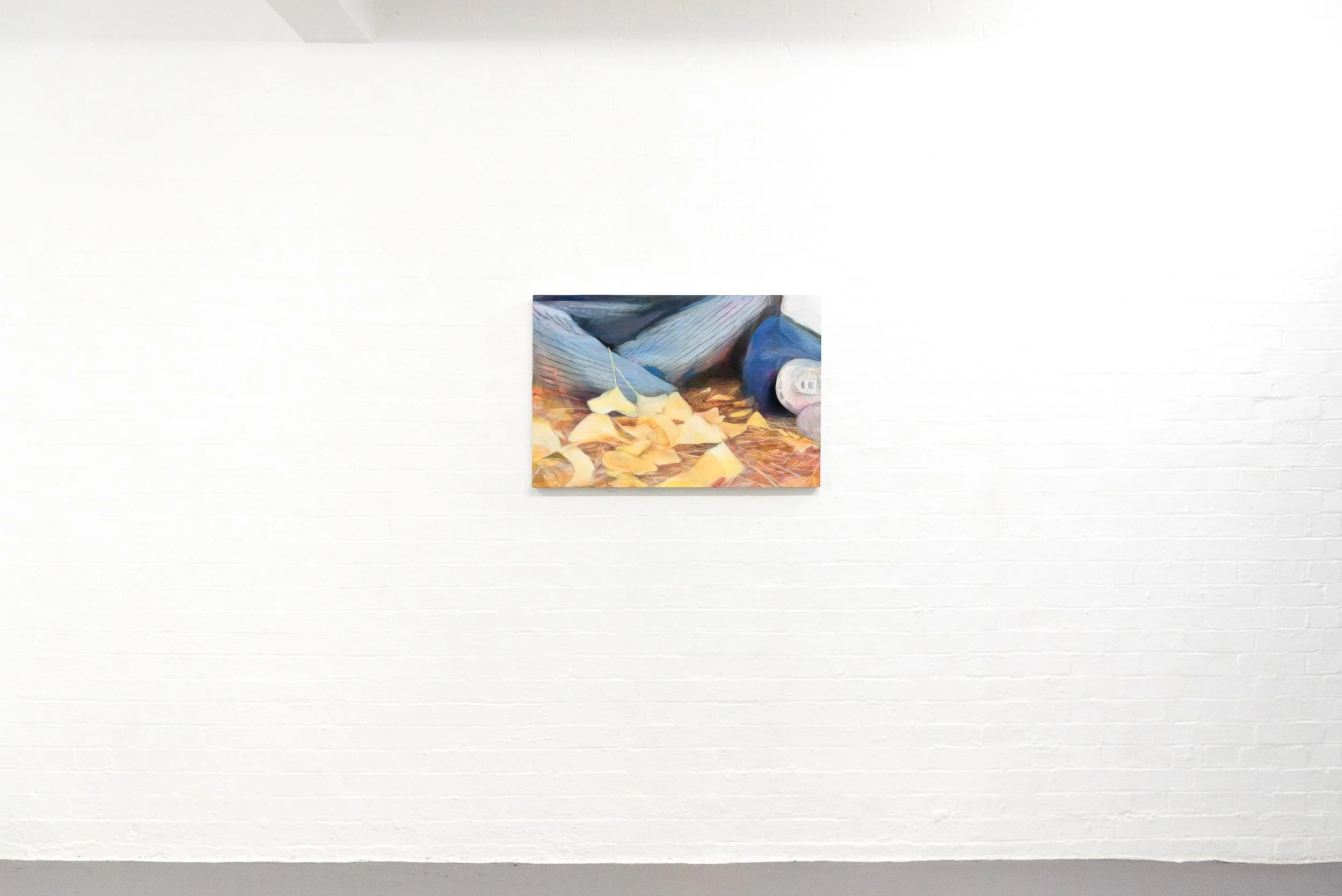 A small abstract painting hanging on a white brick gallery wall.