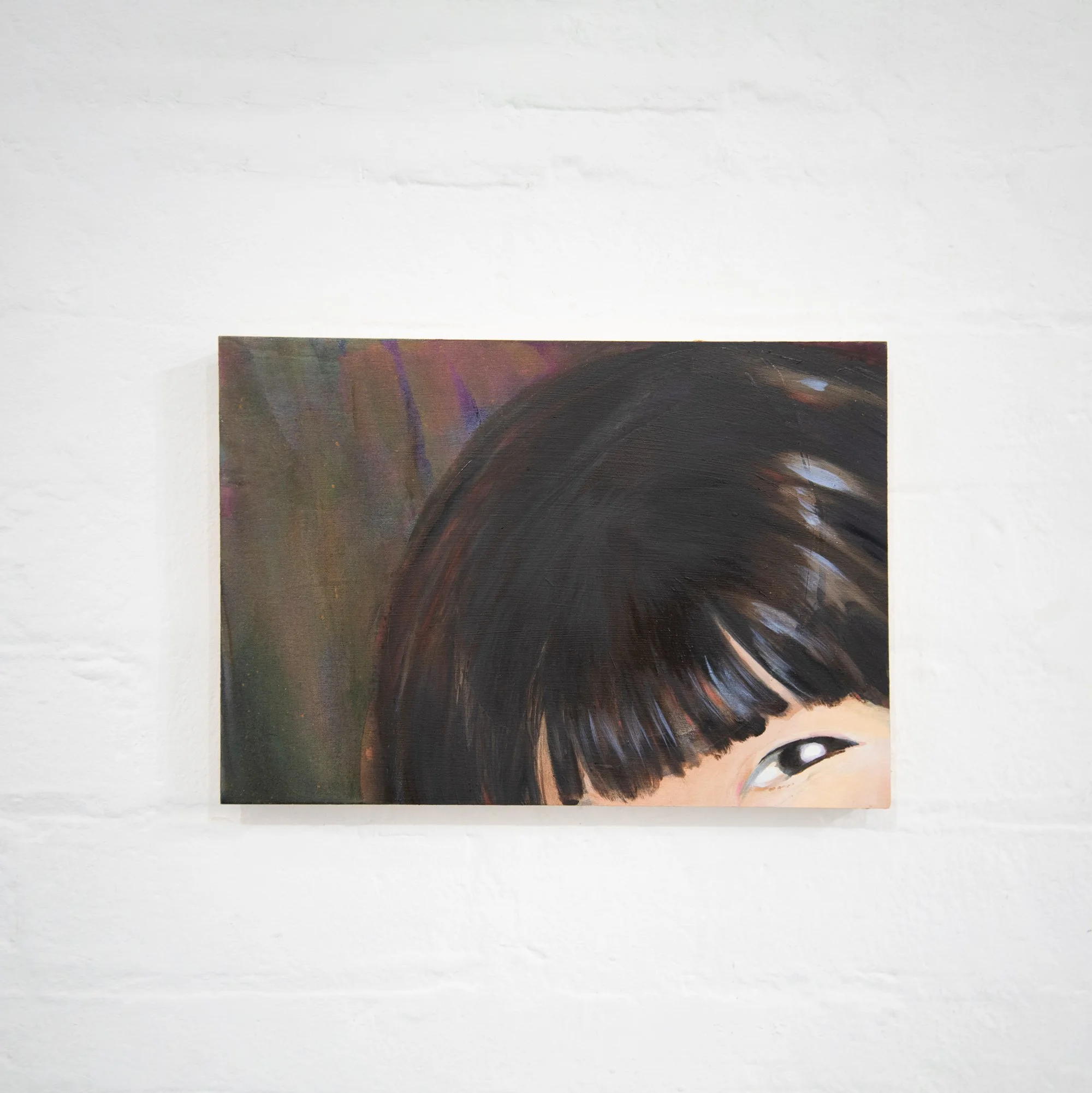 Close-up of a painting featuring a detailed eye with intricate brushstrokes, positioned against a textured white wall background.