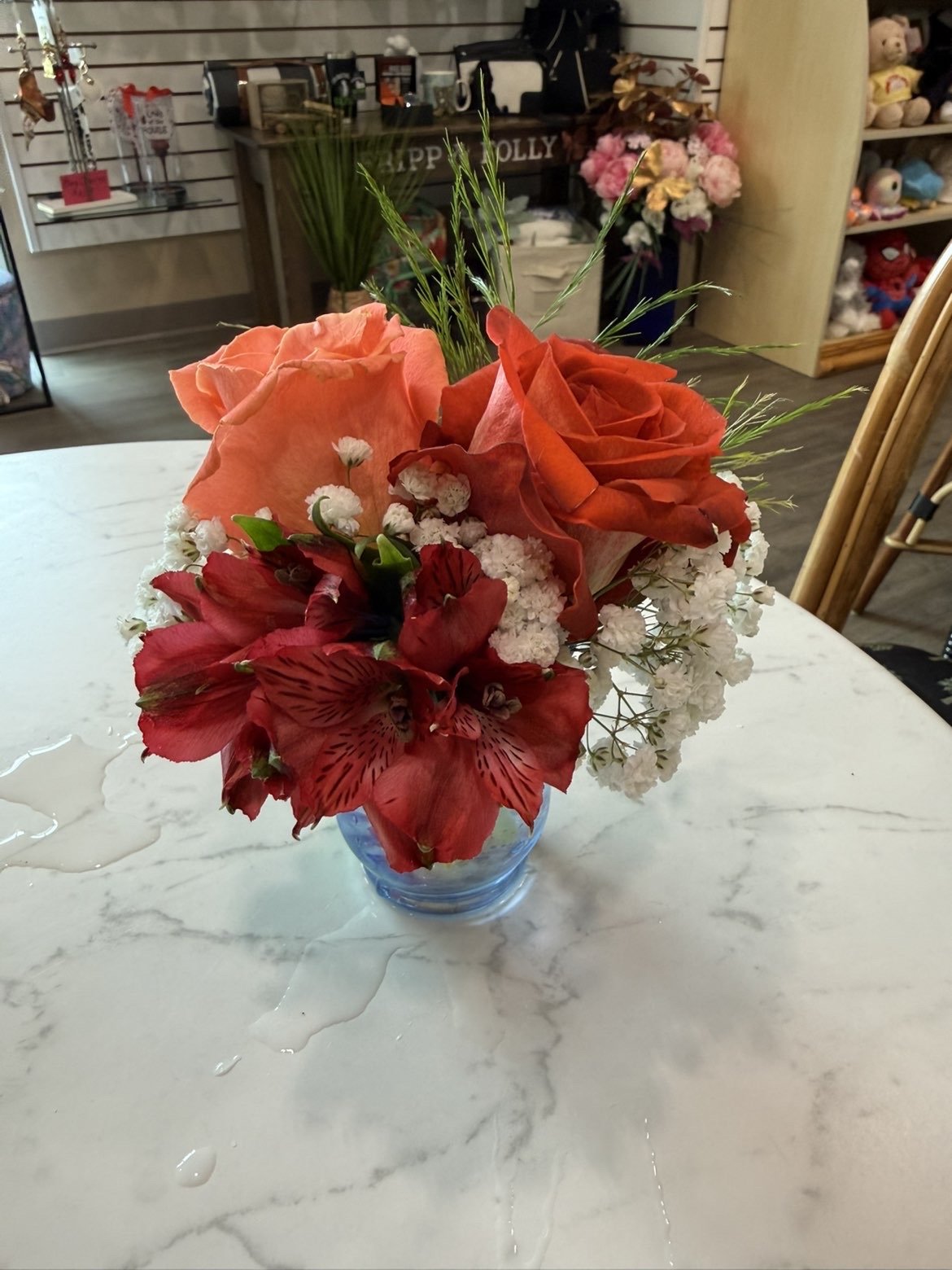 Vase de fleurs colorées avec des roses, des alstroemérias et des petites fleurs blanches sur une table en marbre.