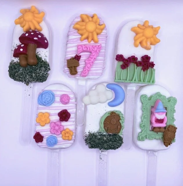 Handcrafted fairy-themed treats decorated in whimsical pastel colors with flowers, clouds, and moon details for a seventh birthday celebration.