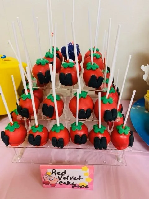 Handcrafted round cake pops inspired by the energy-restoring tomatoes from Nintendo's Kirby, created for a birthday celebration.