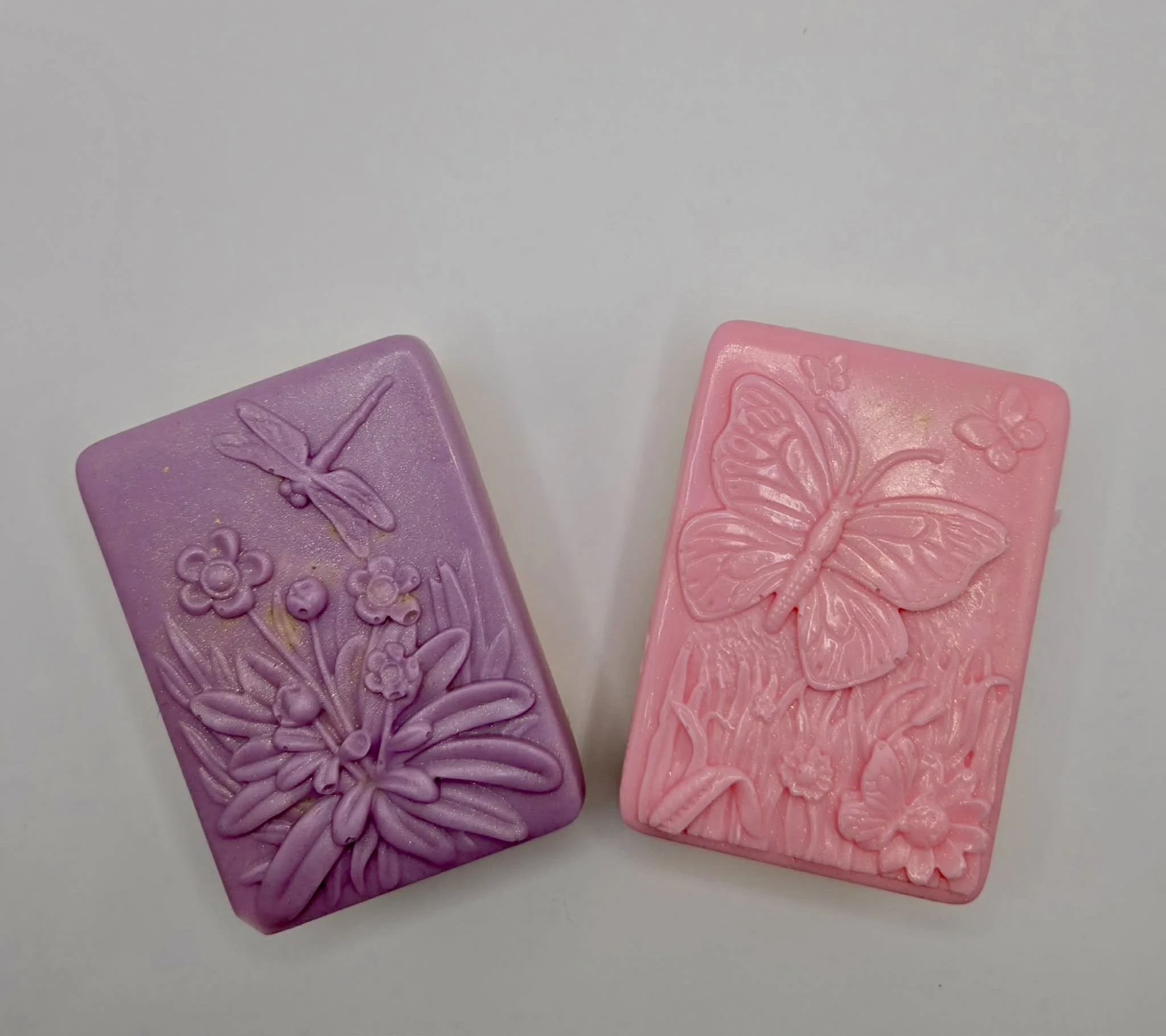 Two handcrafted Luna Creations chocolate-dipped Rice Krispies treats in pink and purple, decorated with butterfly designs.