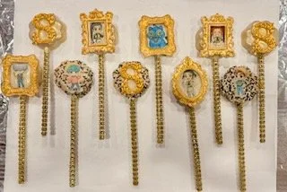 Handcrafted Luna Creations flat, round cake pops decorated with gold picture frames and colorful K-pop demon hunter-inspired designs for a birthday celebration.