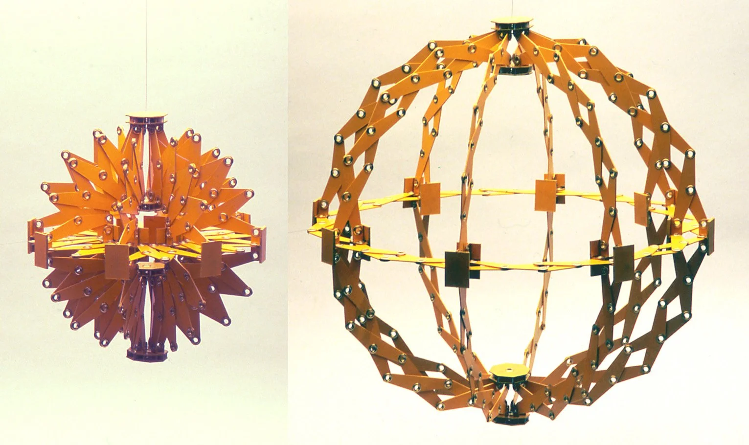 Two geometric structures made of orange and yellow interconnected pieces, resembling 3D polygonal shapes.
