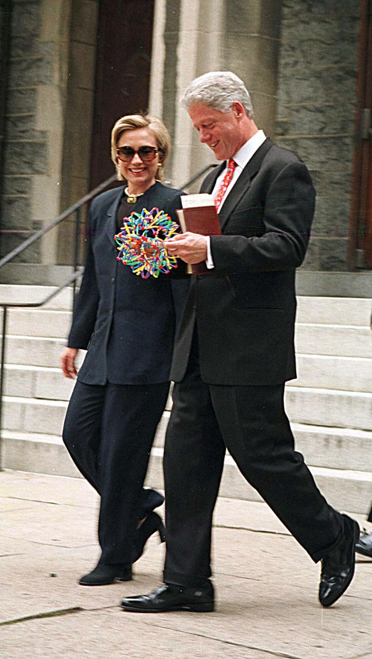 Bill and Hillary Clinton with Hoberman Sphere, smiling and laughing together.