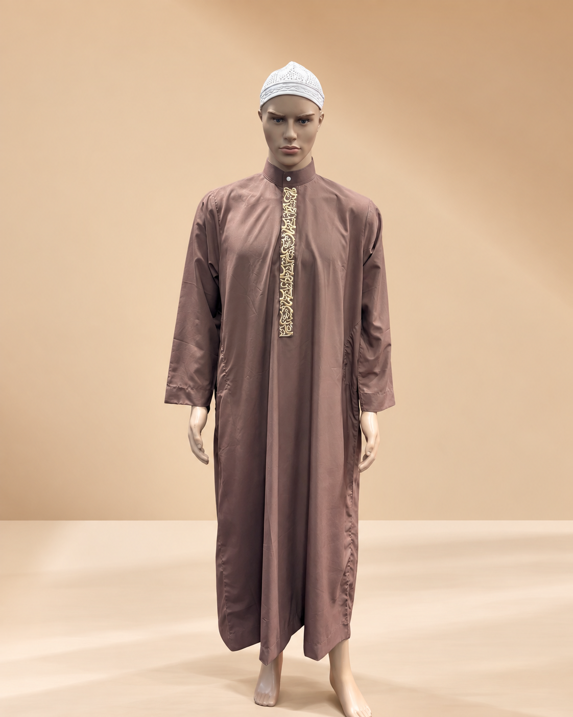 Mannequin wearing a traditional brown thobe with embroidered front, white cap, on a plain background.