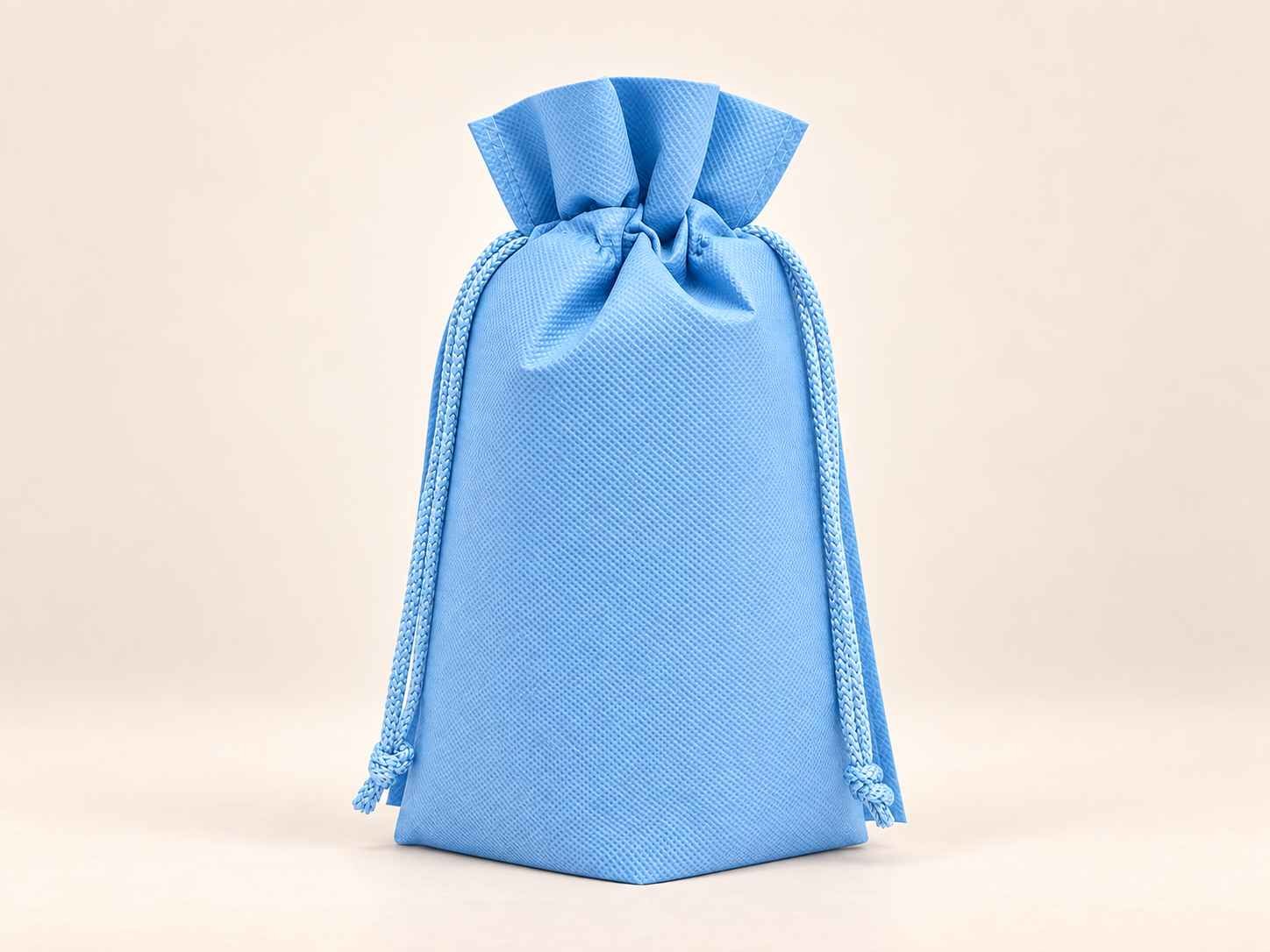 Bolsa en cambrel caramelo fuelle abajo reutilizable color azul con cordones sobre un fondo neutro.