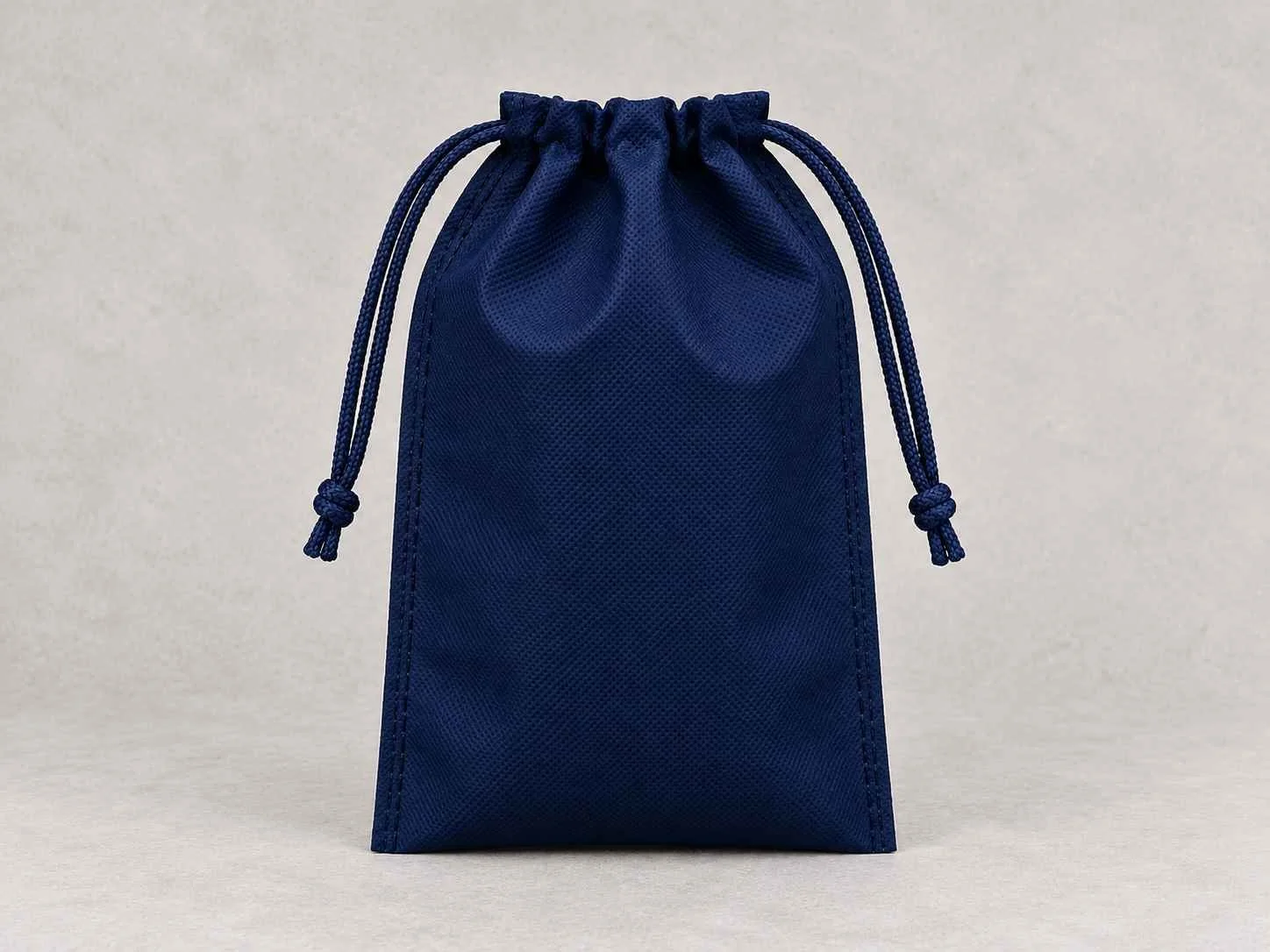 blue cambrel bag with knots at the ends, standing upright on a light background.