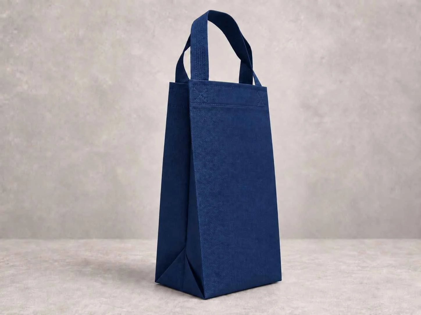 A tall, blue tote bag standing on a light surface with a plain light background.