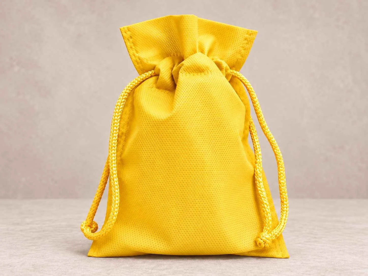 Bolsa de cambrel reutilizable caramelo  con cordón color amarillo sobre un fondo neutro.