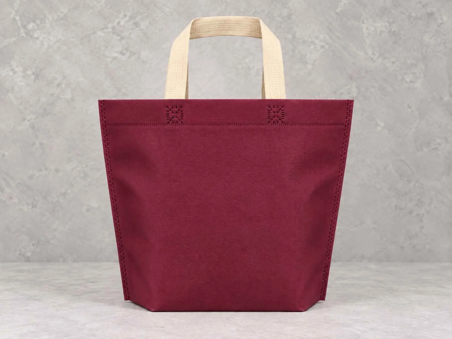 Bolsa de cambrel reutilizables plana manija con fuelle abajo color vinotinto con manijas beige sobre un fondo neutro. 