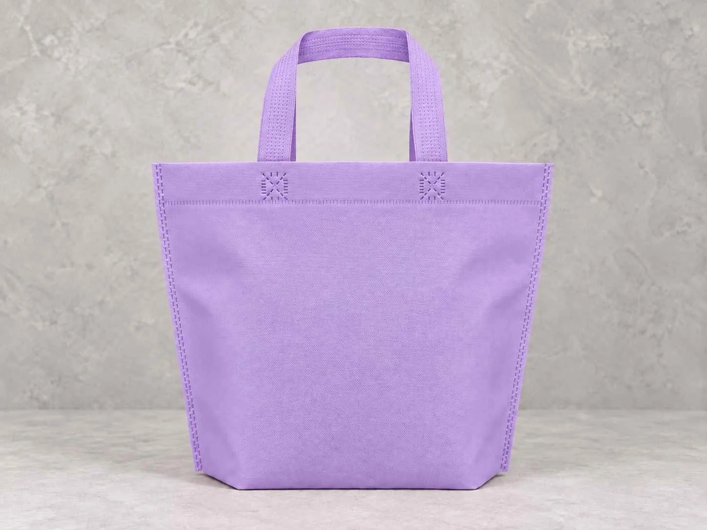 Bolsa de cambrel reutilizables plana manija con fuelle abajo color lila sobre un fondo neutro. 