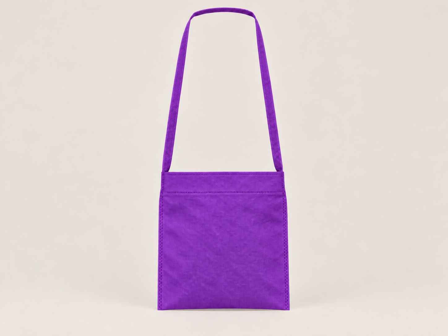 Bolsa de cambrel reutilizable manos libre color morado sobre un fondo neutro. 