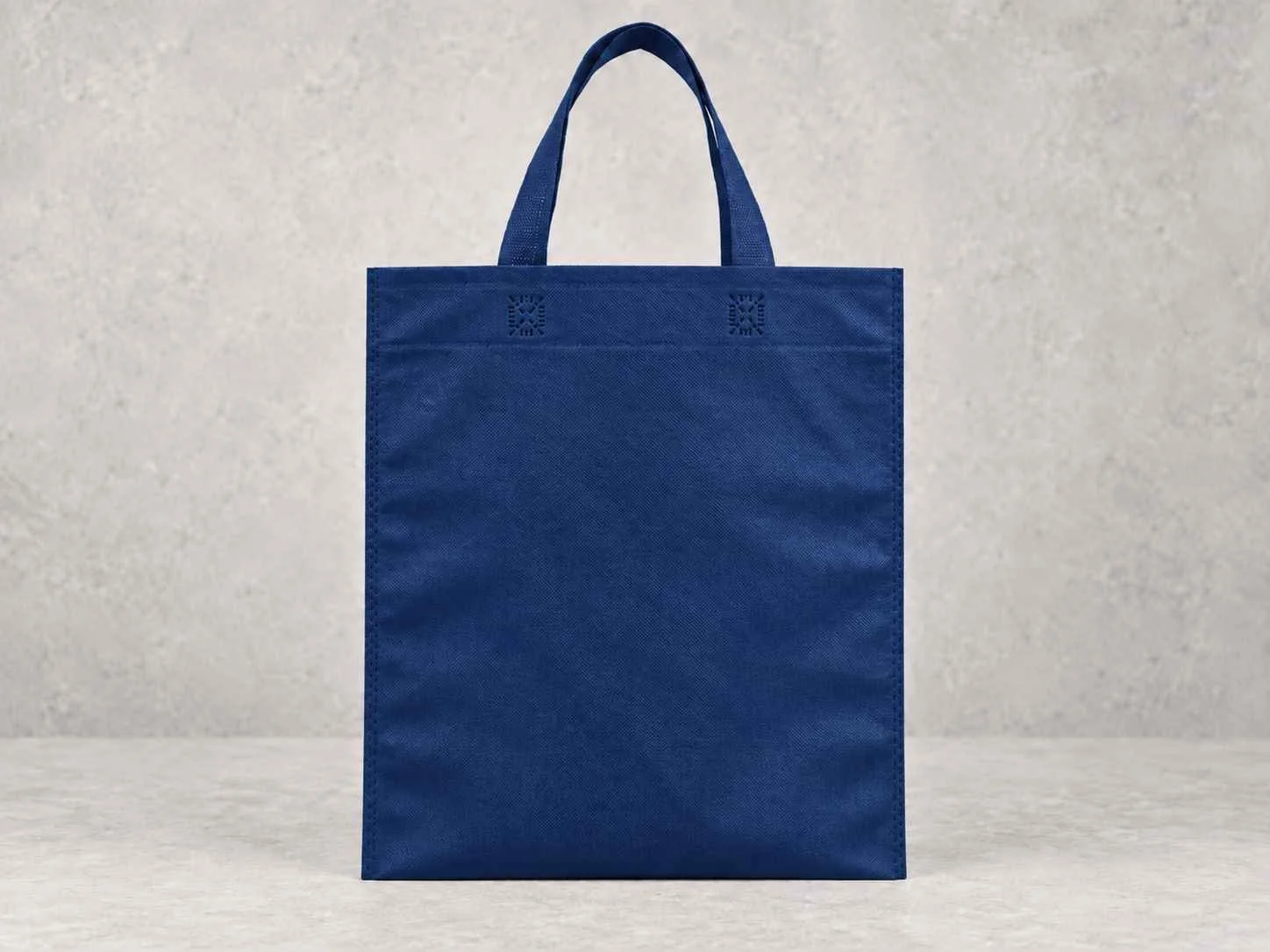 Blue reusable shopping bag standing on a gray surface against a gray wall
