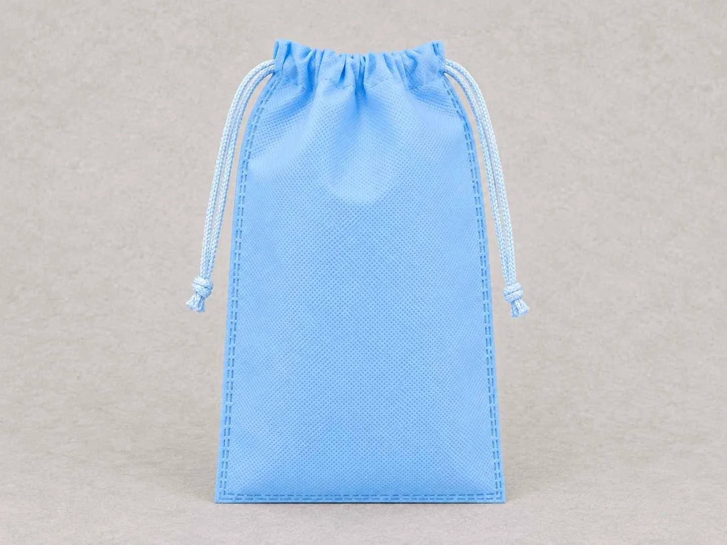 Light blue cambrel bag with doble cordón set against a plain gray background.