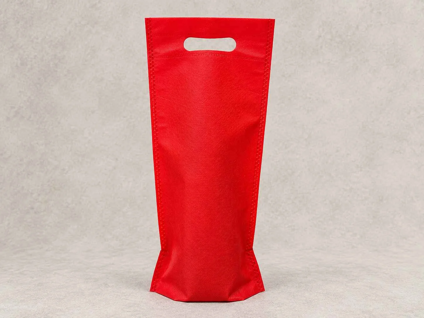 Red fabric tote bag with handle cutout, standing on a neutral background.