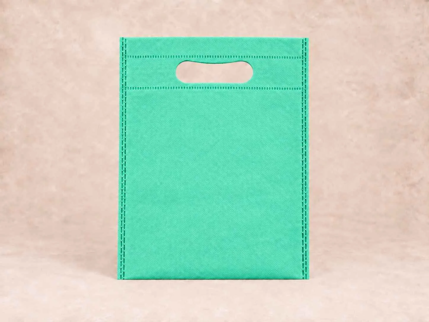Bolsa de cambrel reutilizable plana troquelada color verde jade sobre un fondo neutro.