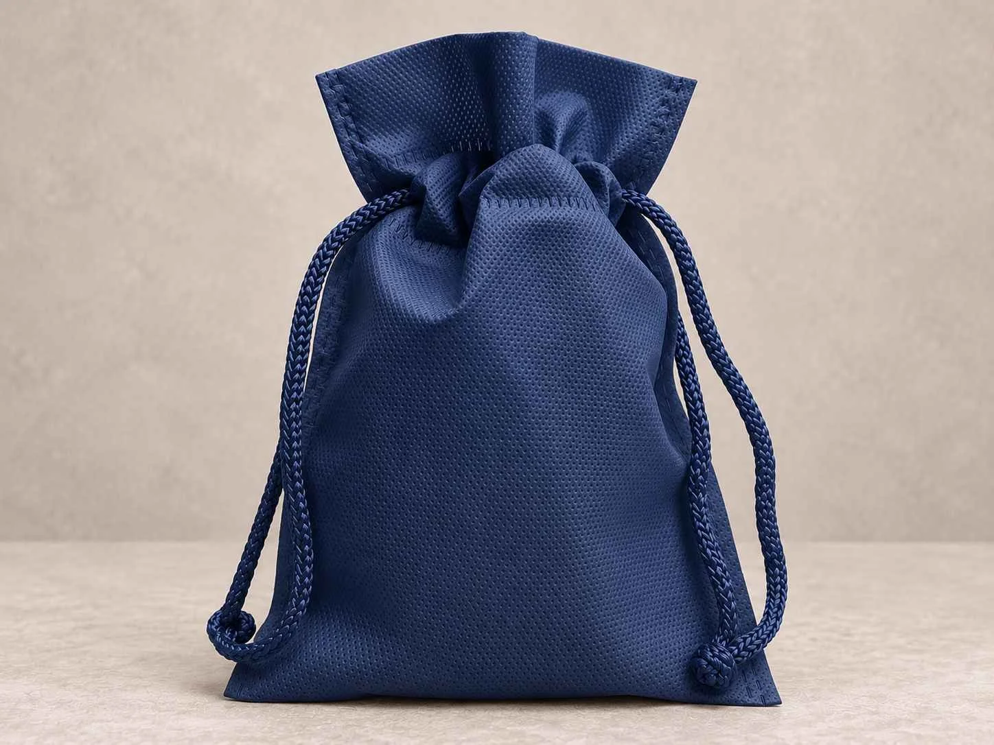 Bolsa de cambrel reutilizable caramelo con cordón color azul oscura sobre un fondo neutro.