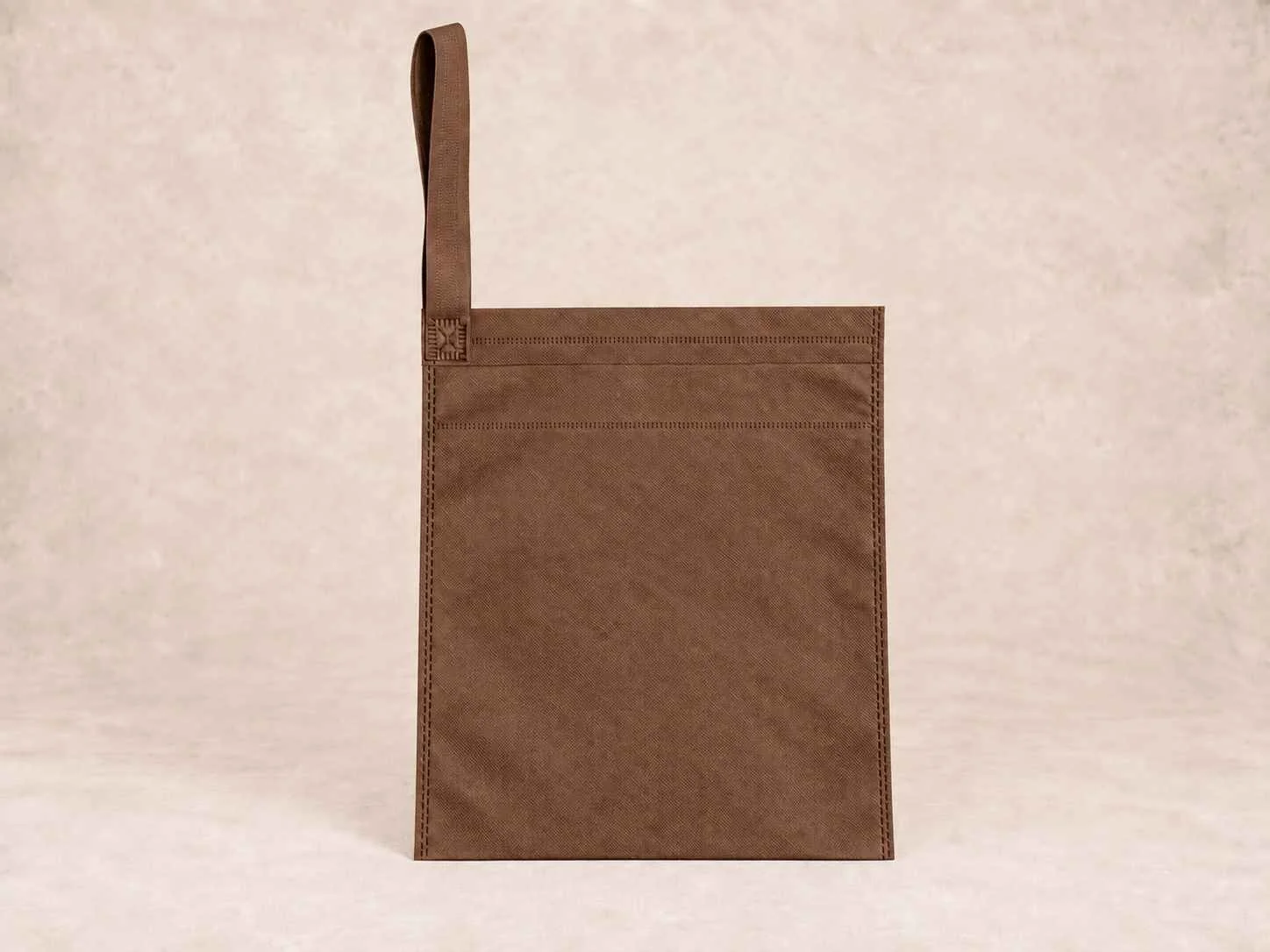  bolsa de cambrel reutilizable carro color café de pie vertical sobre una superficie neutra contra un fondo neutro.
