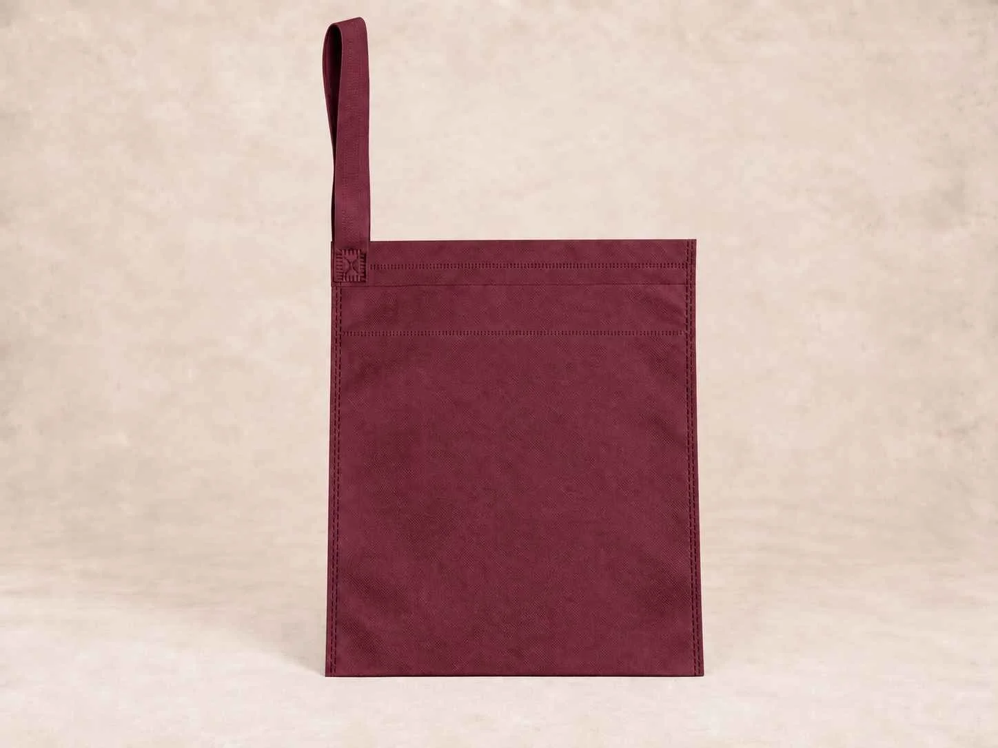  bolsa de cambrel reutilizable carro  color vinotinto de pie vertical sobre una superficie neutra contra un fondo neutro.