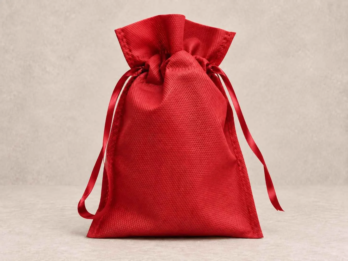 Bolsa de cambrel reutilizable caramelo roja con cinta roja sobre un fondo neutro.
