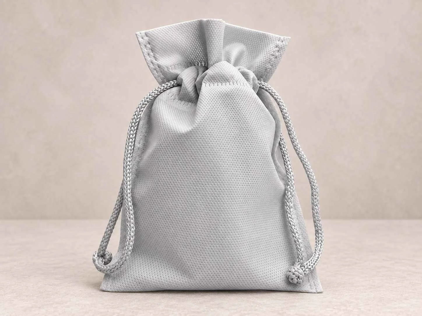 	
Bolsa de cambrel reutilizable caramelo con cordón color gris sobre un fondo neutro.