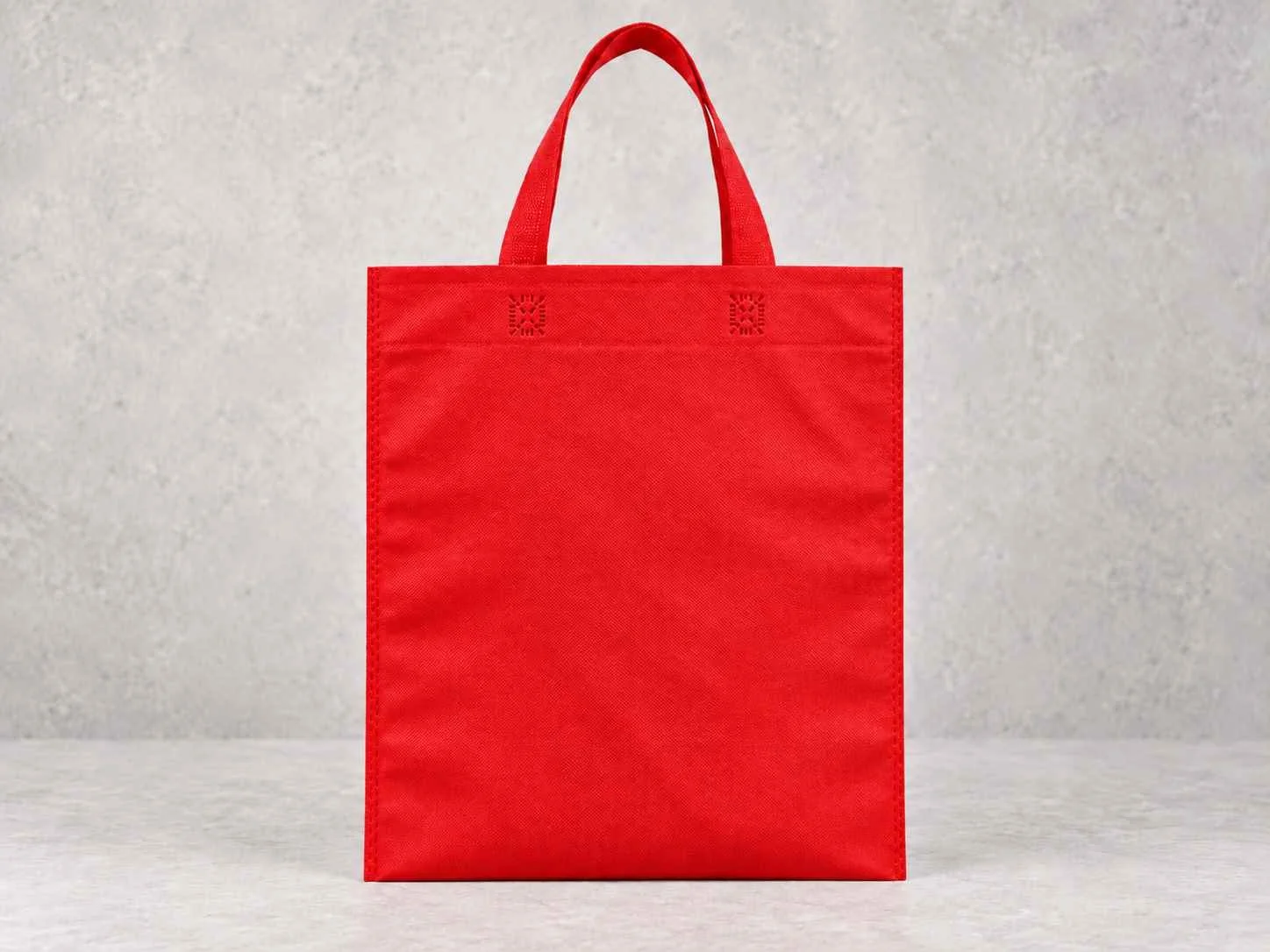 Red reusable shopping bag on a neutral background.