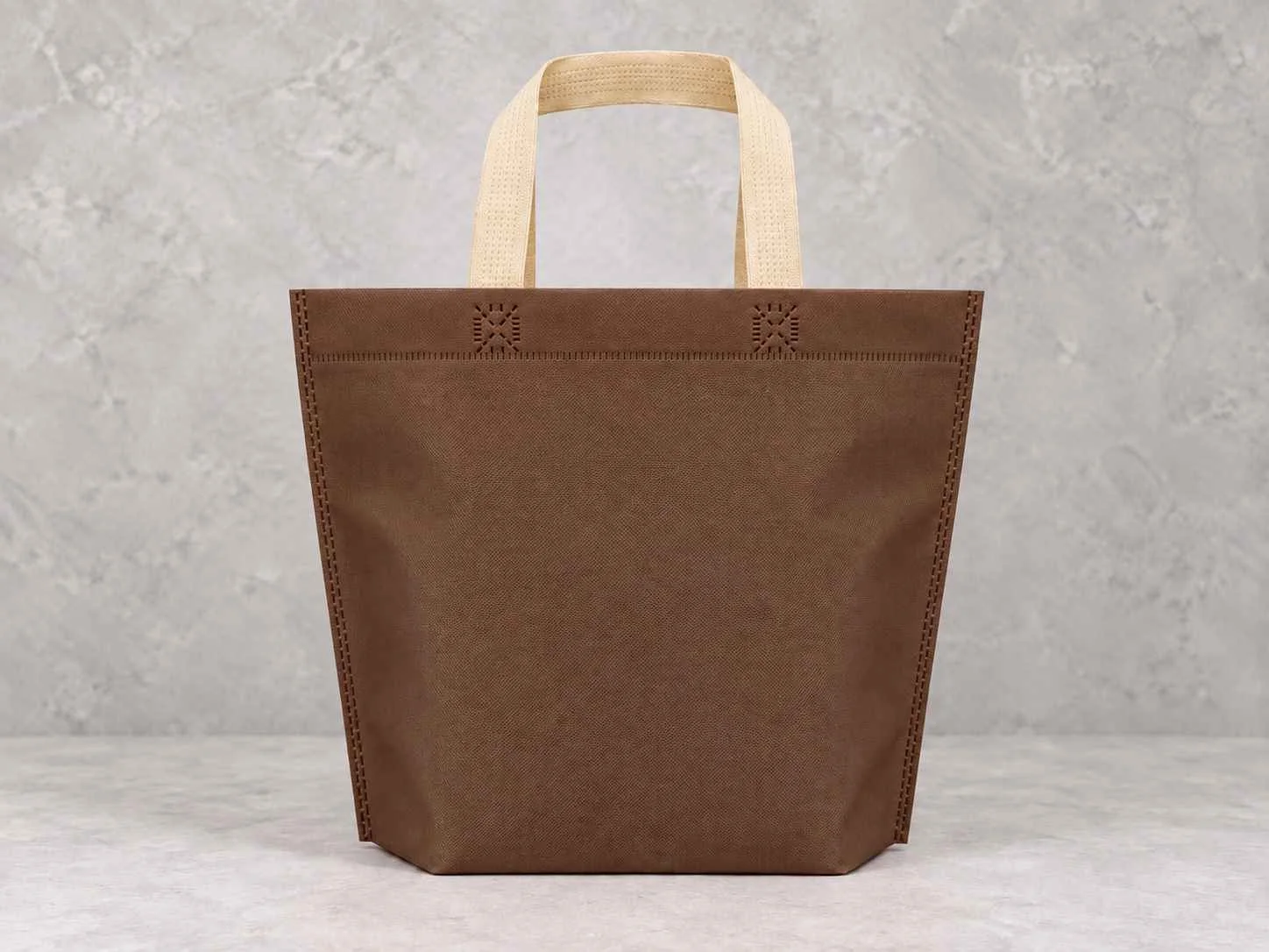 Bolsa de cambrel reutilizables plana manija con fuelle abajo color café con manijas beige sobre un fondo neutro. 