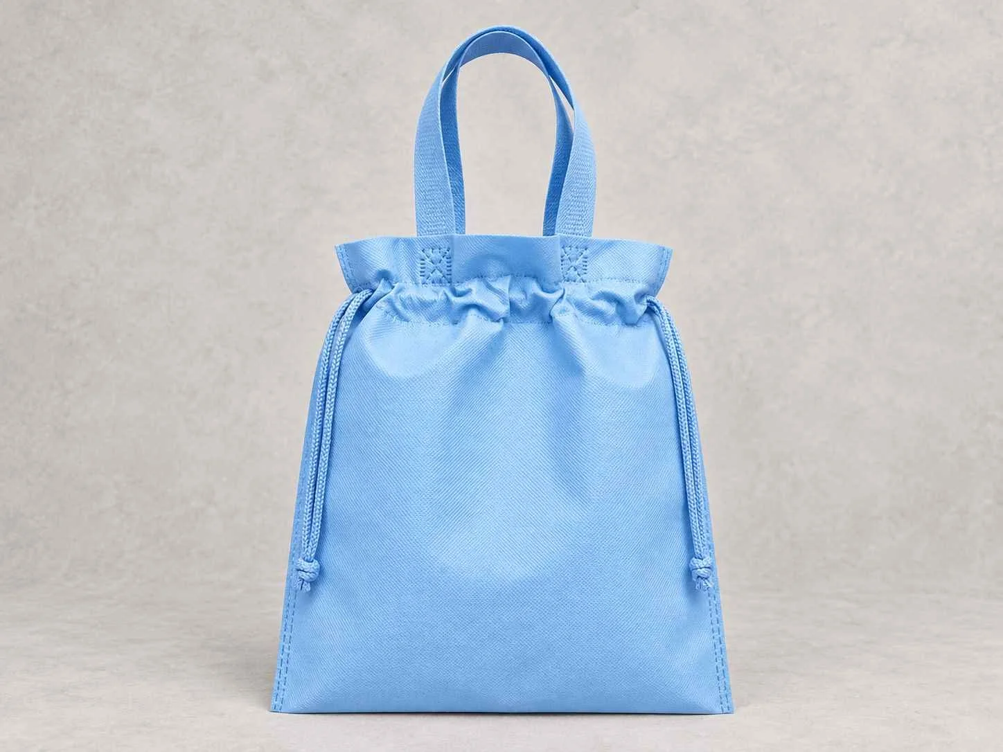 	
Una bolsa reutilizable plana fusión azul bebé de cambrel de pie vertical sobre una superficie neutra contra un fondo neutro.