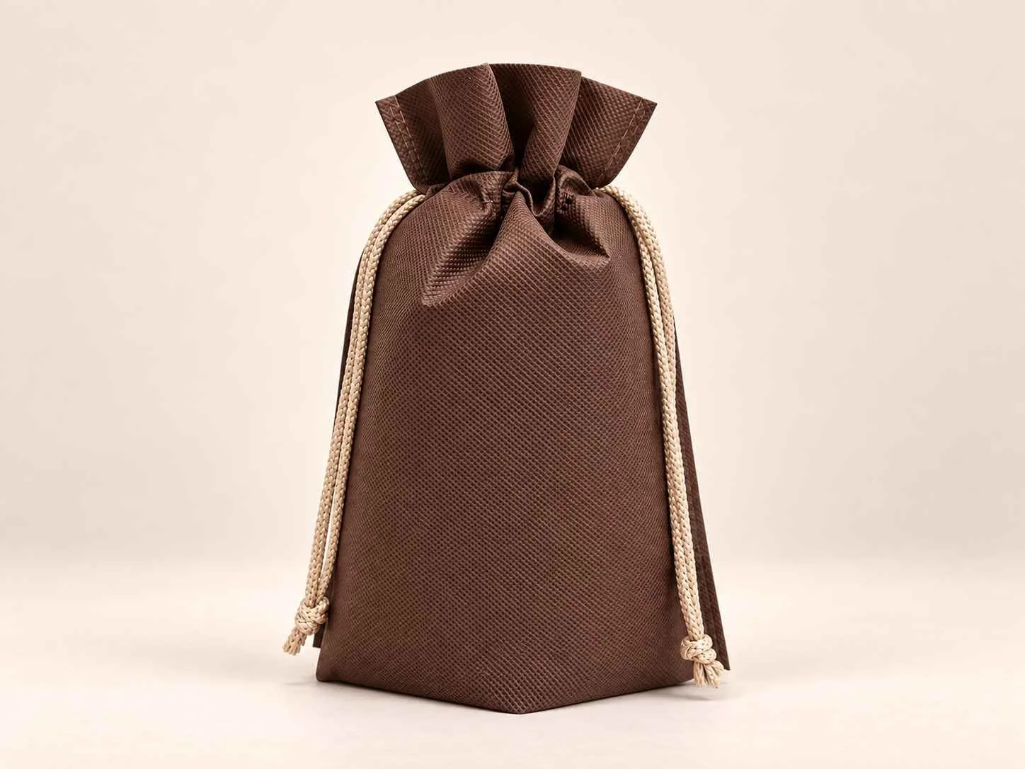 Bolsa en cambrel caramelo fuelle abajo reutilizable color café con cordones beige sobre un fondo neutro.