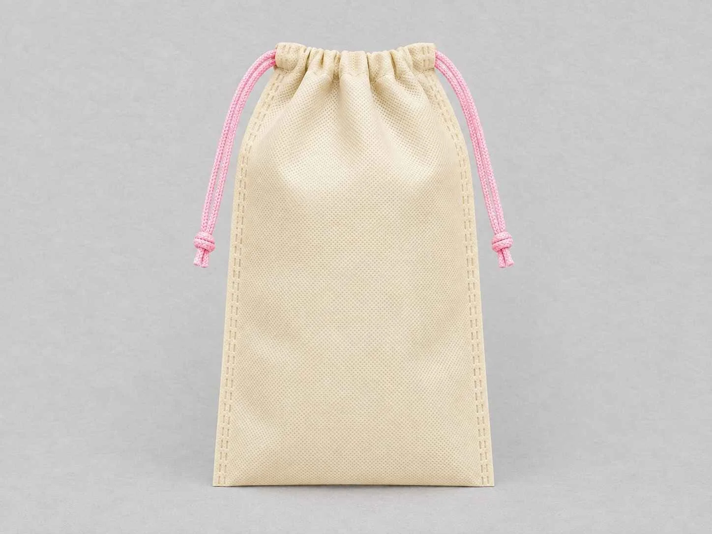 Beige cambrel bag with pink cords on a gray background.