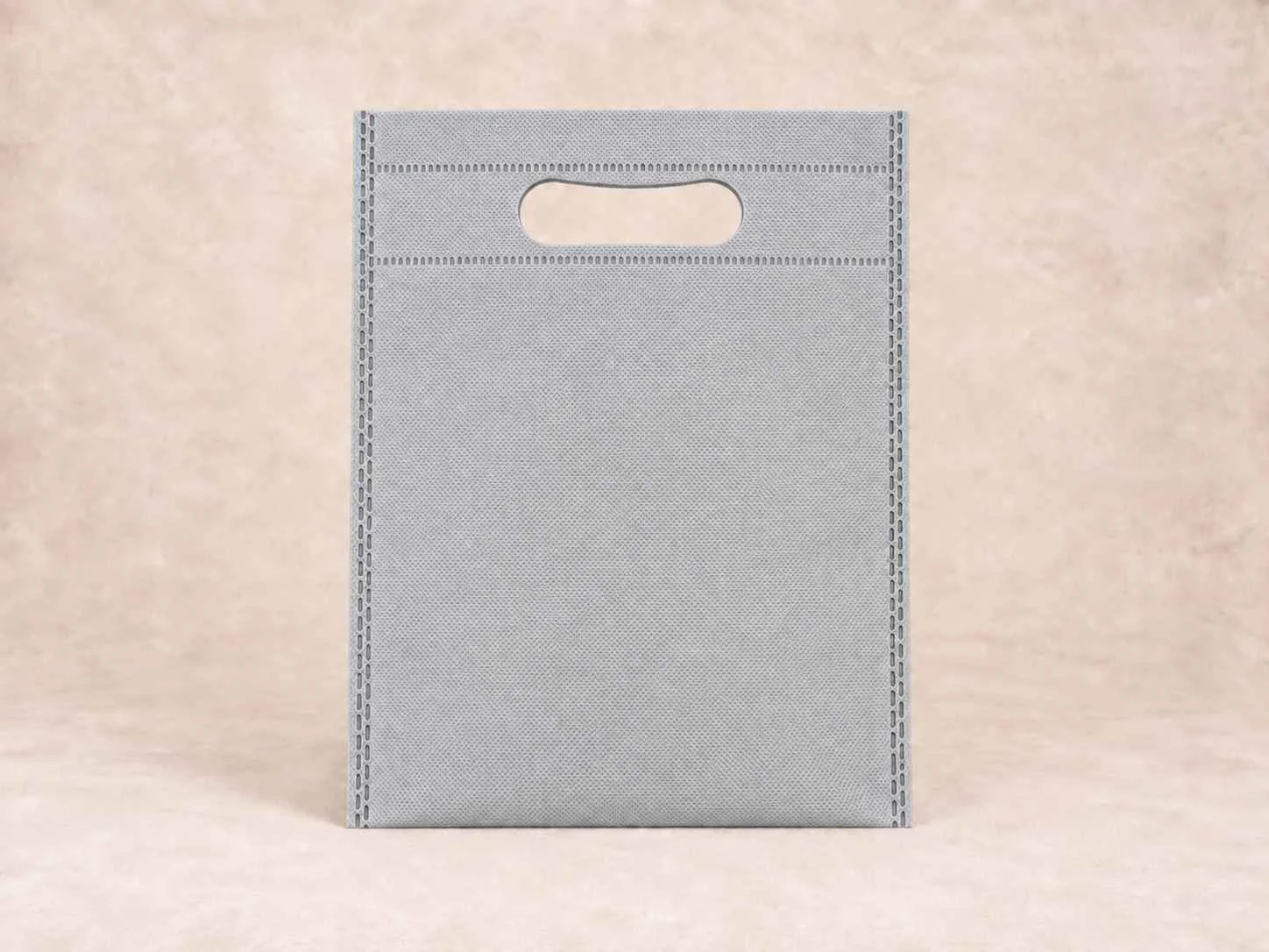 Gray mesh tote bag with a cutout handle at the top, placed on a light background.