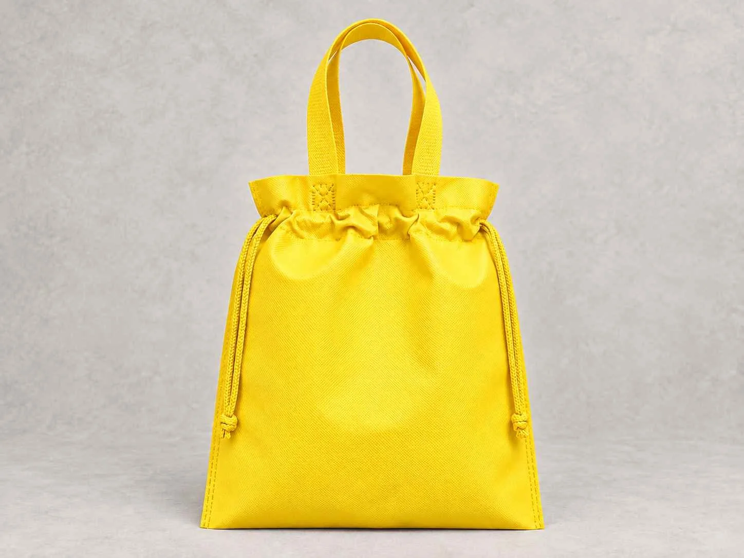  bolsa de cambrel reutilizable plana fusión amarilla de pie vertical sobre una superficie neutra contra un fondo neutro.