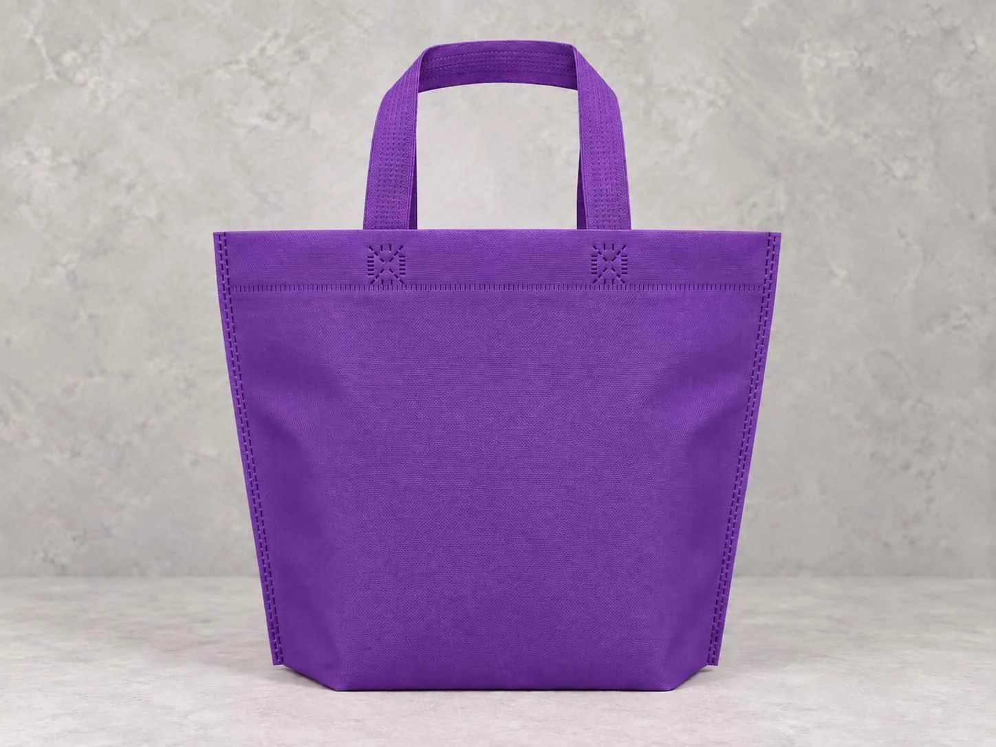 	
Bolsa de cambrel reutilizables manija plana con fuelle abajo color morado con manijas sobre un fondo neutro.