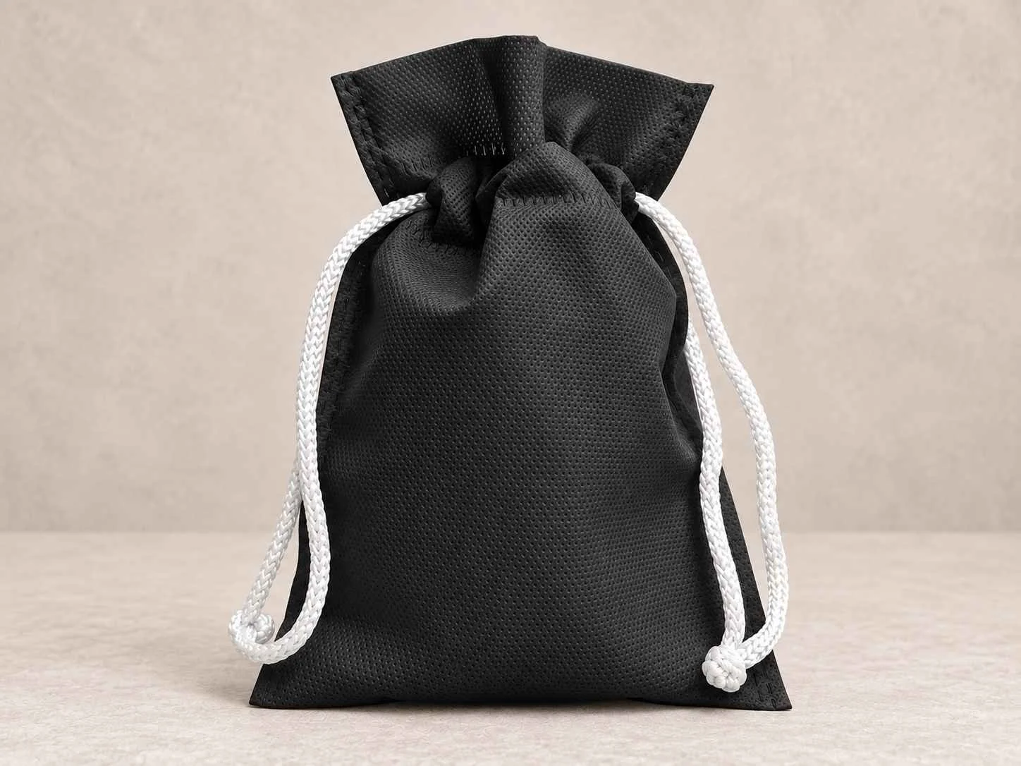 	
Bolsa de cambrel reutilizable caramelo color negra con cordón blanco sobre un fondo neutro.