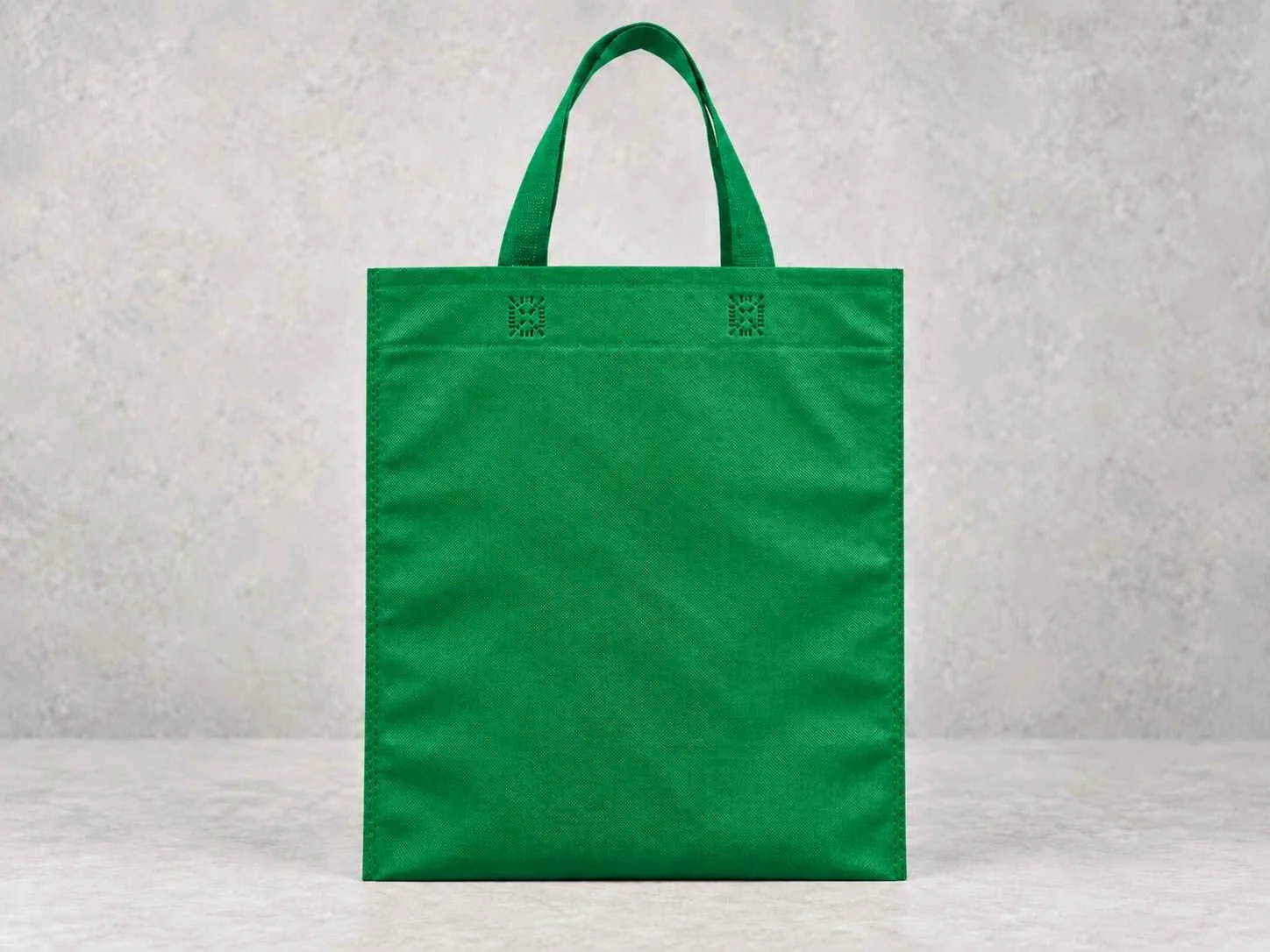 Green reusable shopping tote bag against a neutral background.