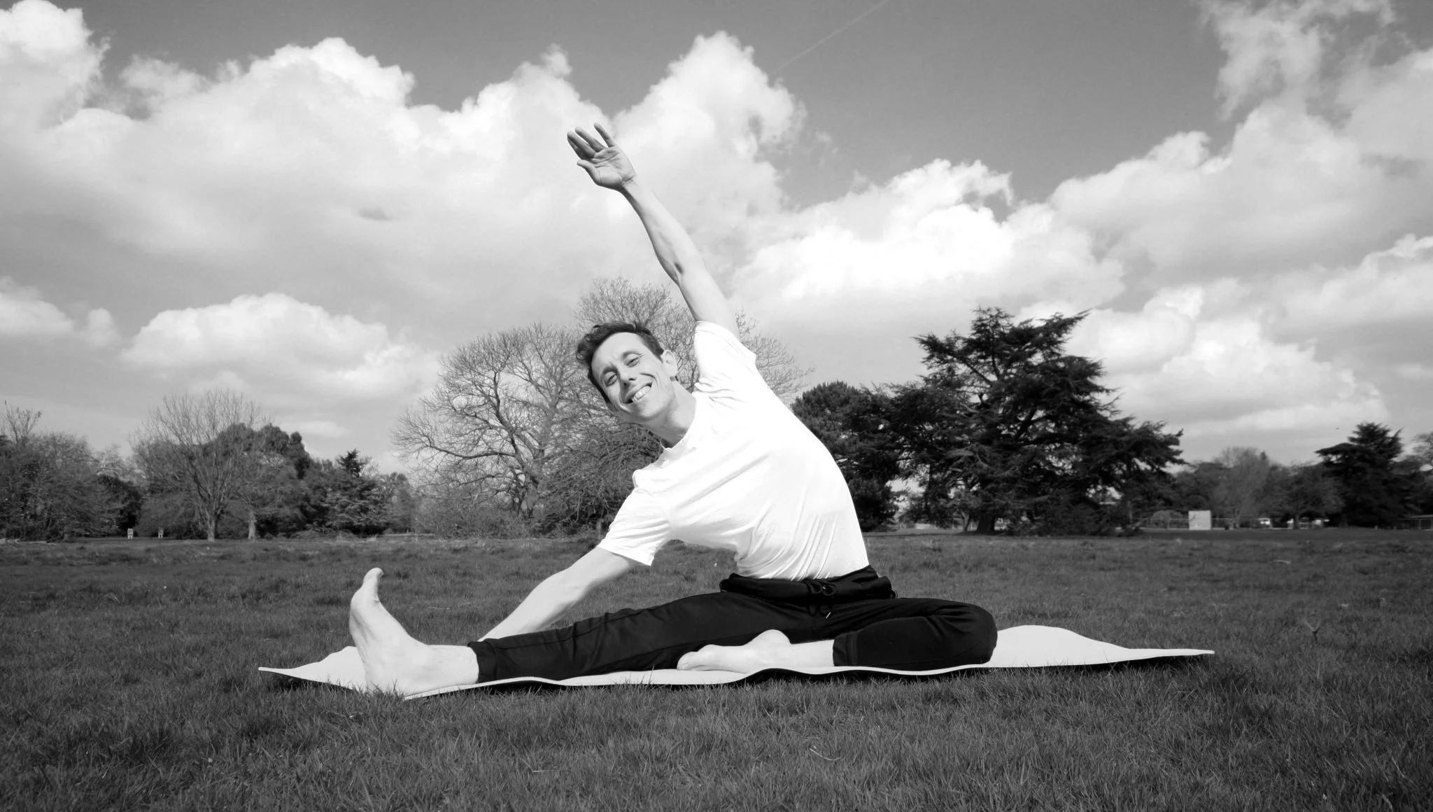 Andrea Molin practising a side stretch among trees in a London park