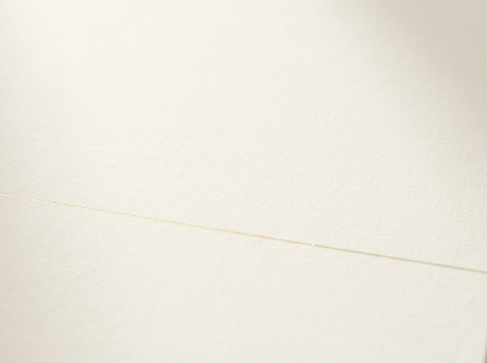 Primer plano de papel o cartulina de color crema o blanco, con una línea diagonal marcada en la superficie.