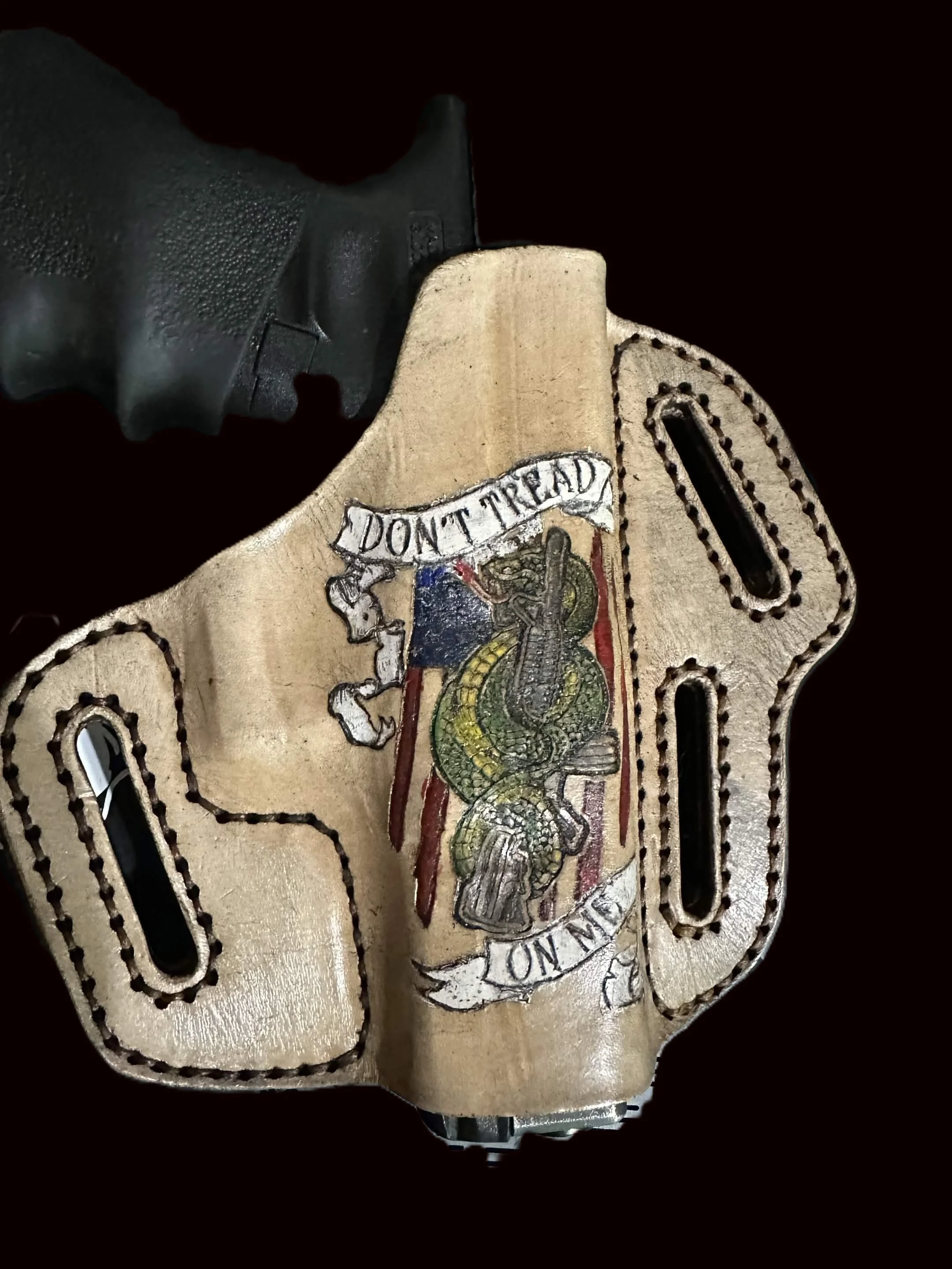 Close-up of a gun holster with a colorful snake and banner reading 'Don't Tread on Me' hand painted on it.