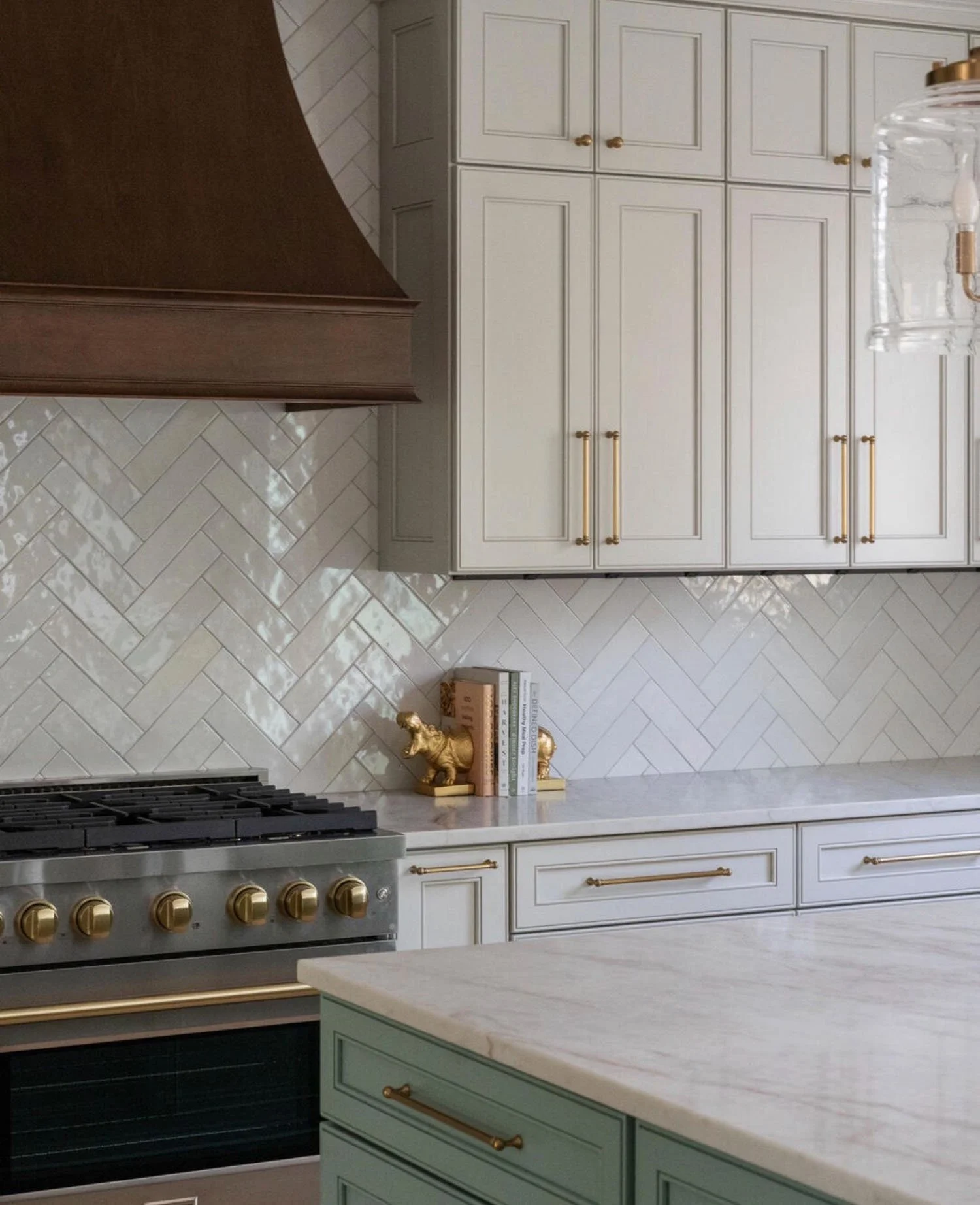 Fully custom kitchen cabinetry made by Rift & Quarter with white cabinets, dark wood range hood, herringbone tile backsplash, and green island in Central Virginia