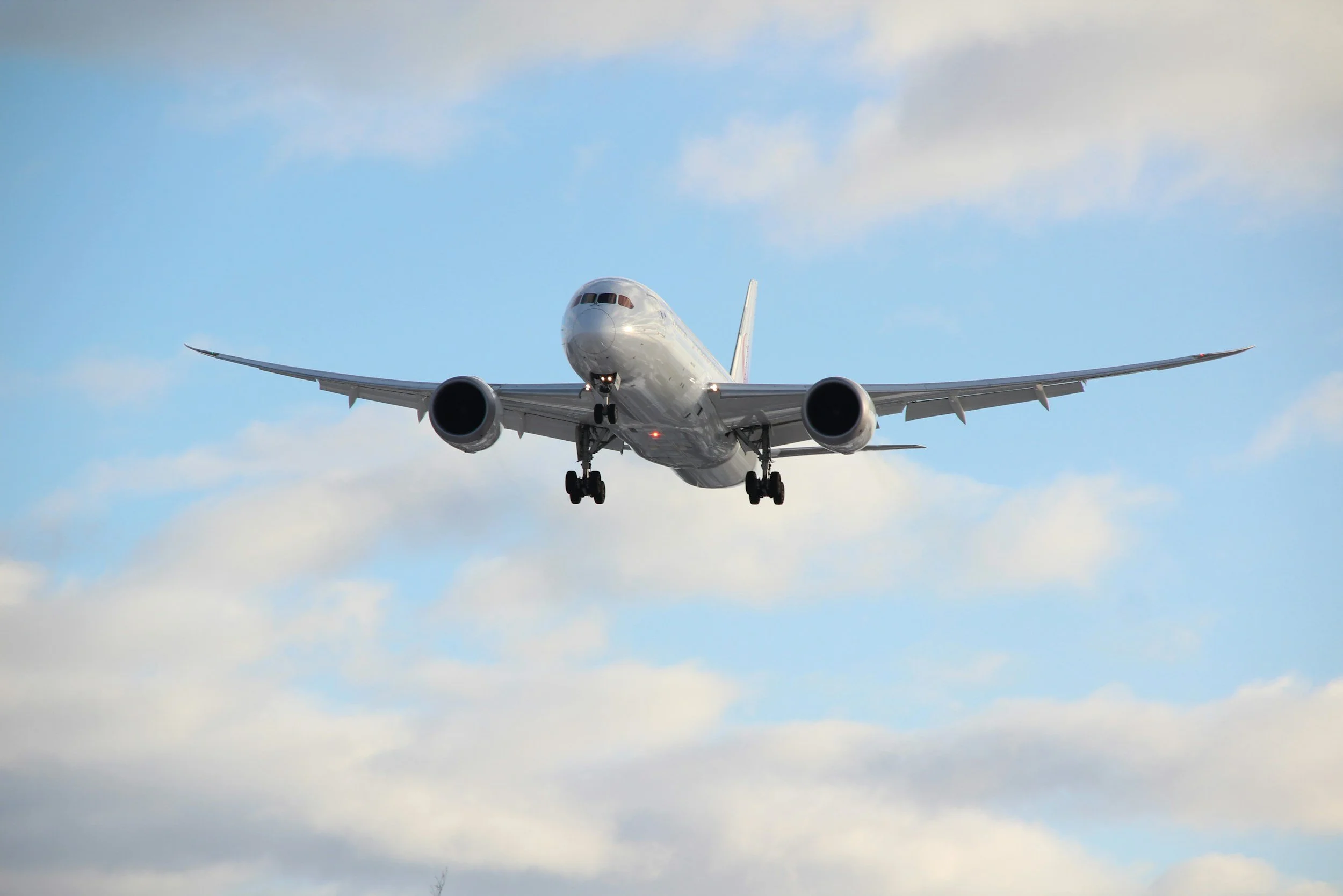 A commercial airplane flying in the sky with blue and cloudy background.