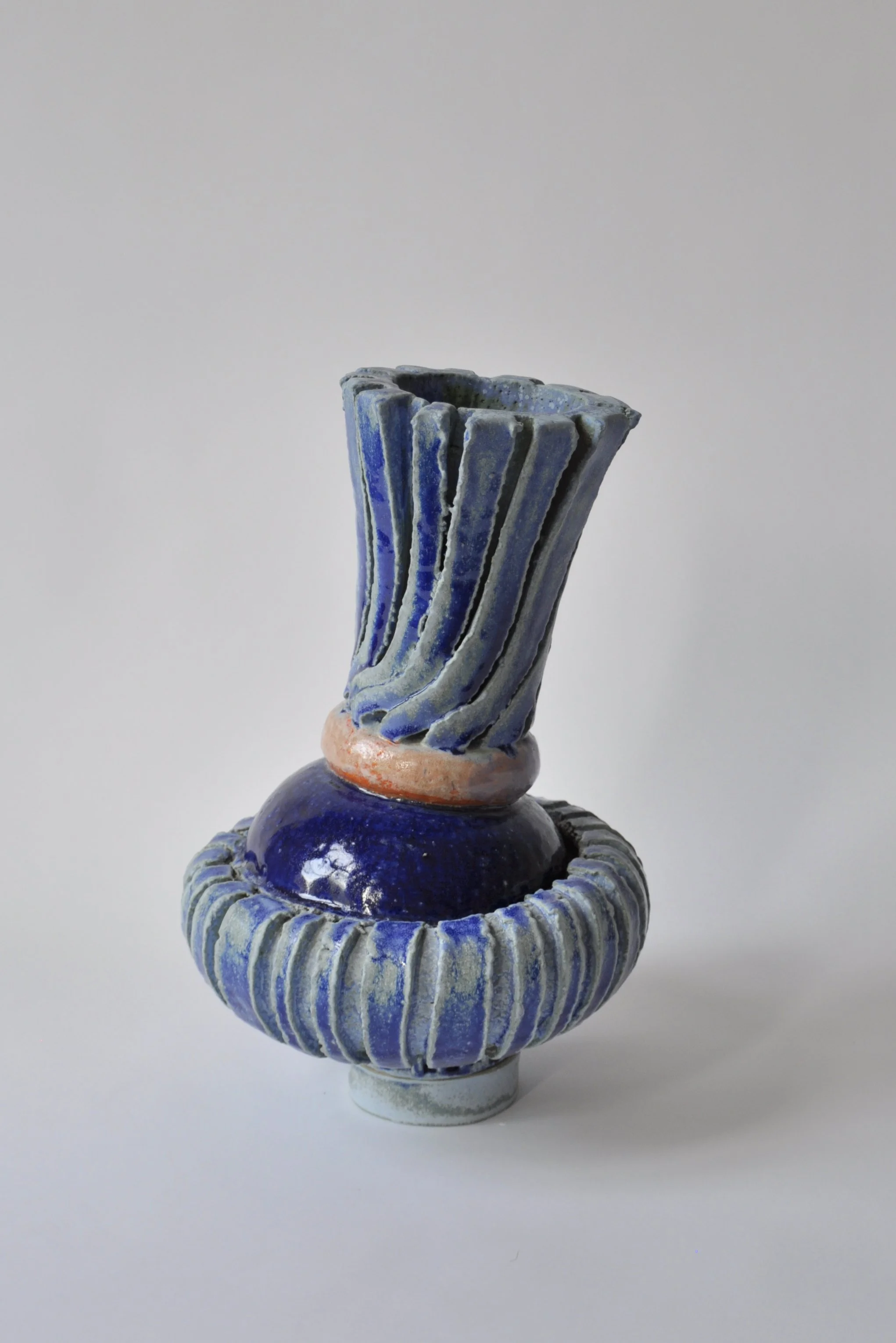 Eine Keramikvase mit blauer und weißer Bemalung, auf einem weißen Hintergrund.