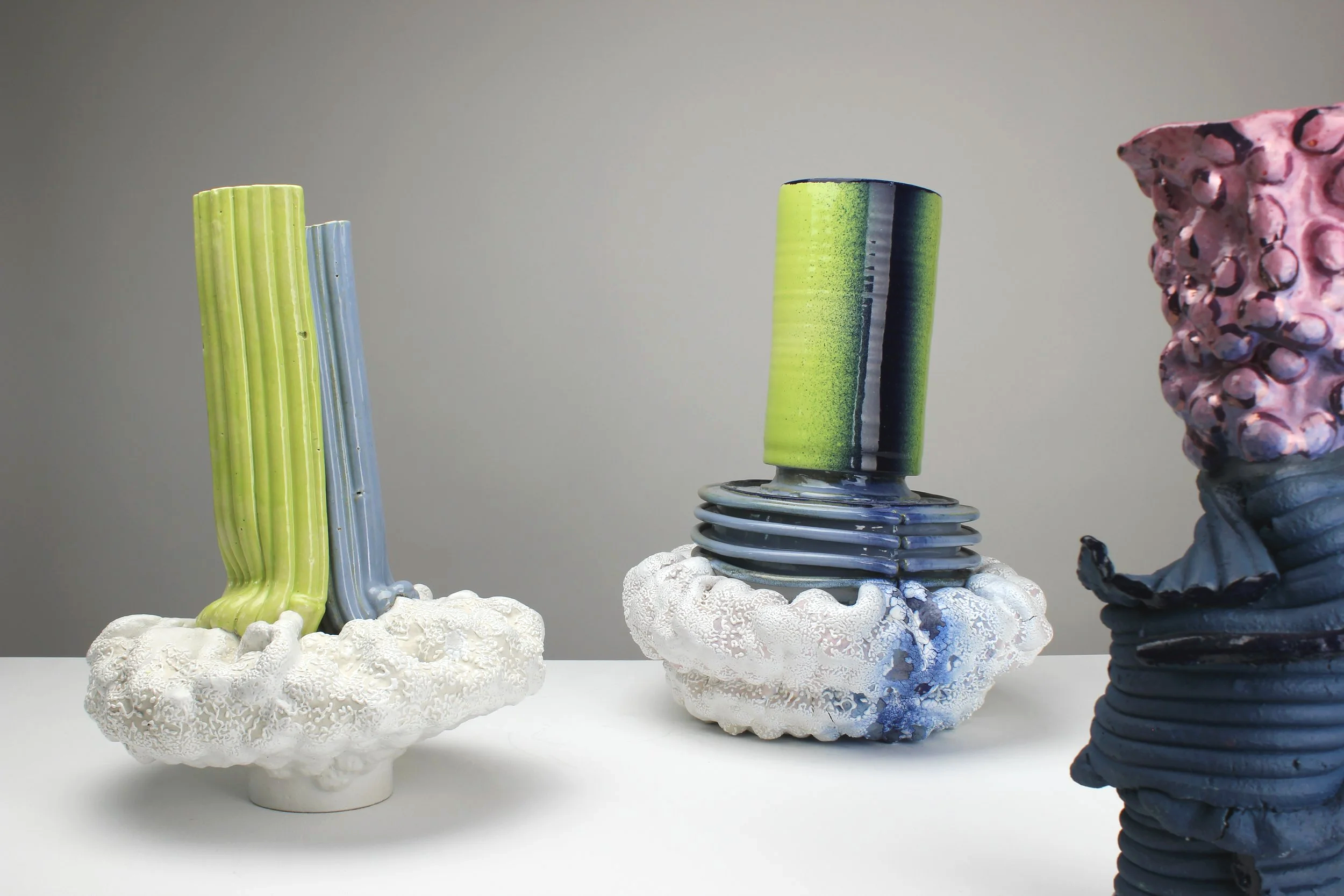 Kunstwerke aus bunten, wavy Zylindern und Gerüsten, die auf weißen, porösen Baseplates aufgestellt sind.